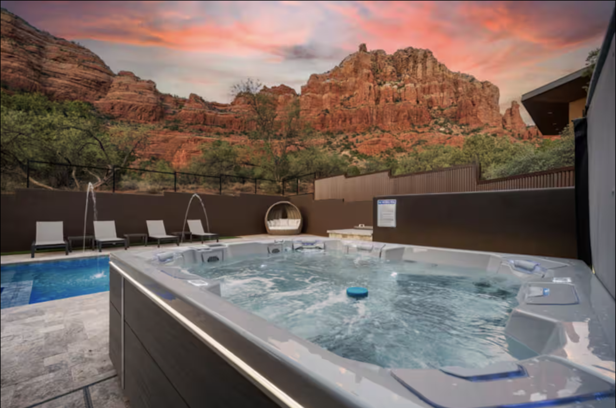 Hot tub with water jets in a backyard with view of red rock mountains at sunset