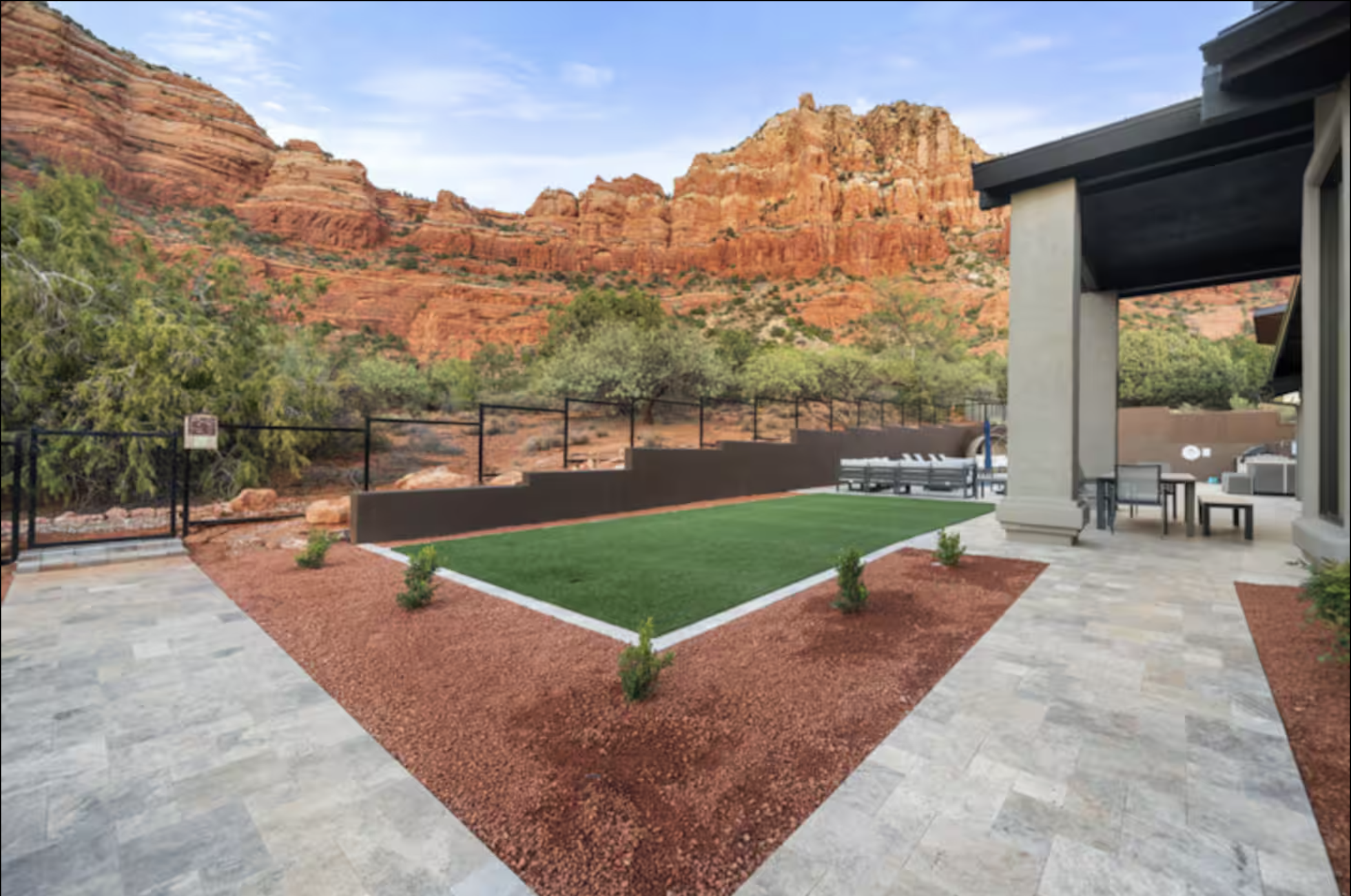 Backyard patio with artificial grass, small shrubs, stone pathway, and mountain view