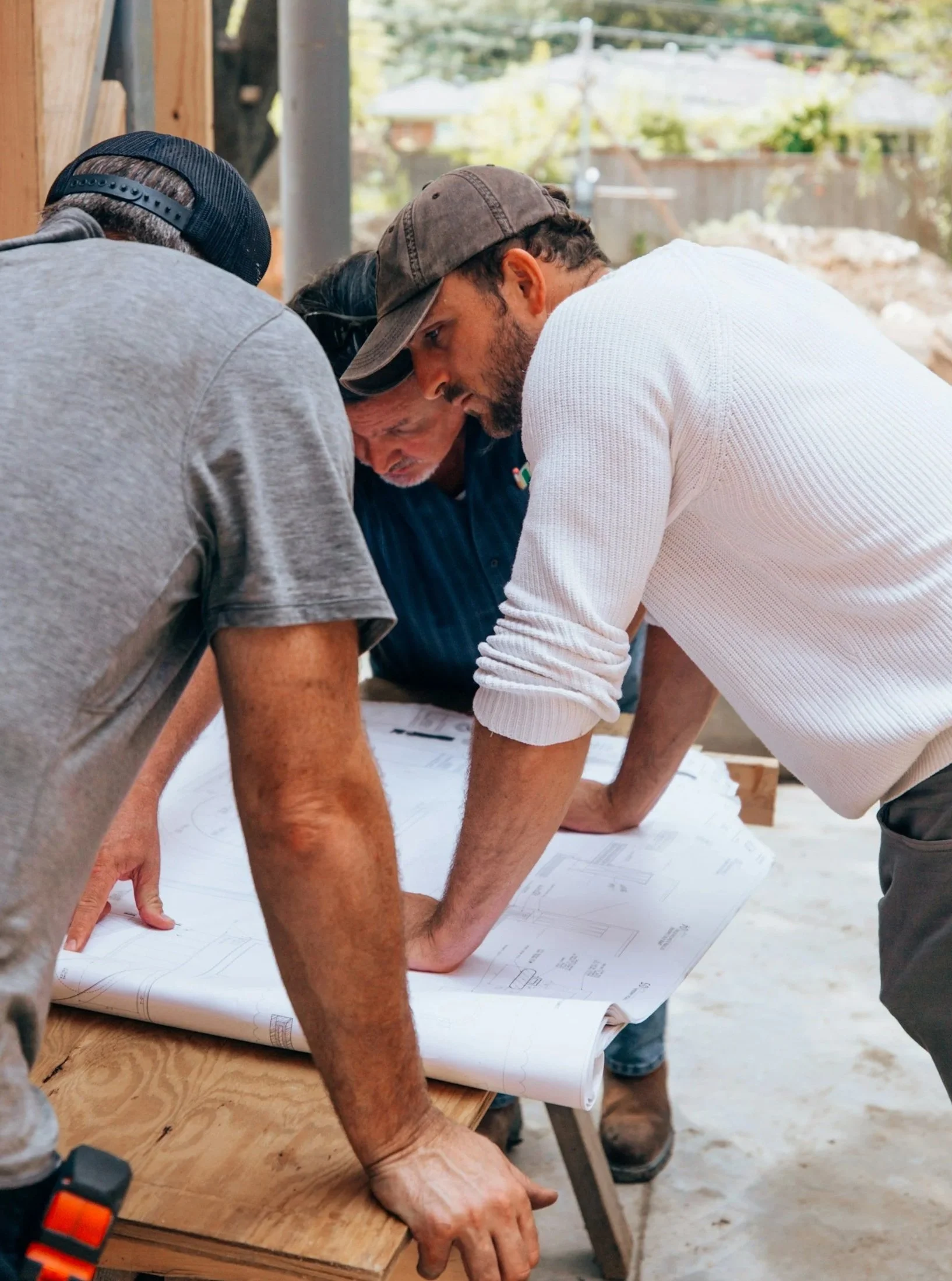 Four men examining blueprints on a construction site.