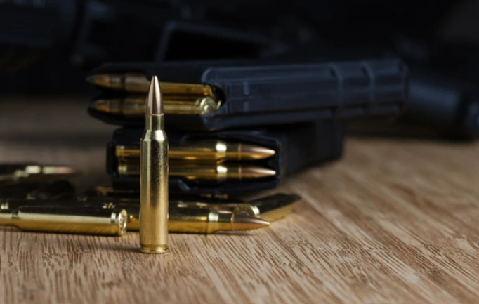 A collection of bullets and gun magazines on a wooden surface.