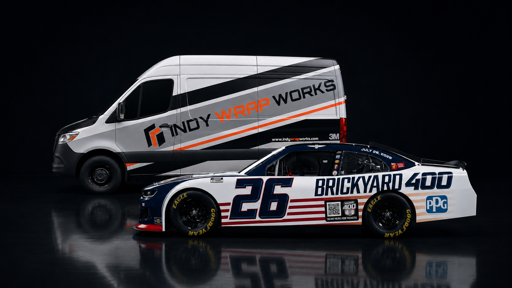 A race car with number 26 and 'Brickyard 400' sponsorship in front of a Indy Wrap Works service van with branding for Indy Wrap Works.