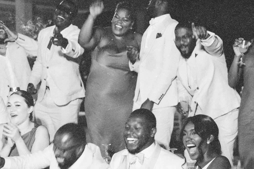 Group of people at a celebration, smiling, dancing, and holding drinks at a lively party.