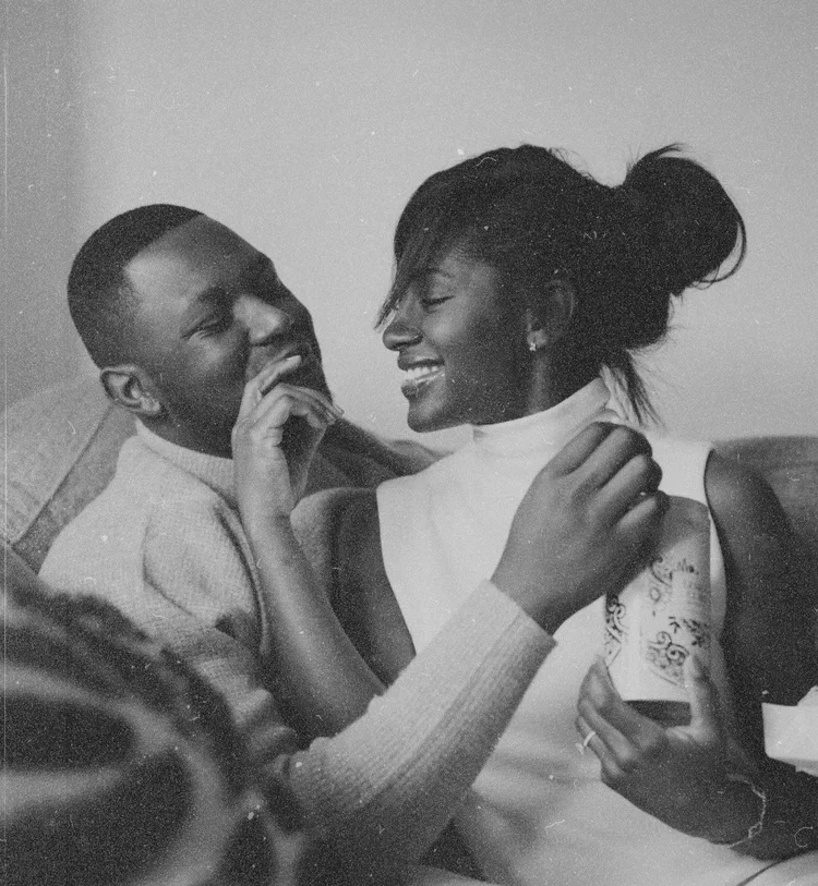 A black and white photo of a happy couple sharing a laughter, with the woman holding a cup.
