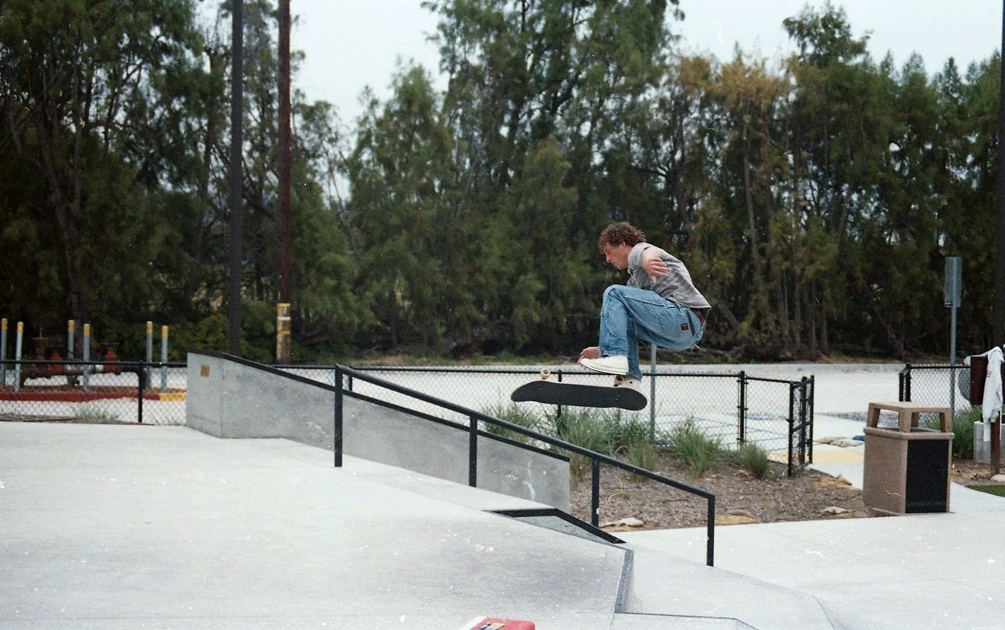 skateboarder performing a kickflip trick at a skate park.