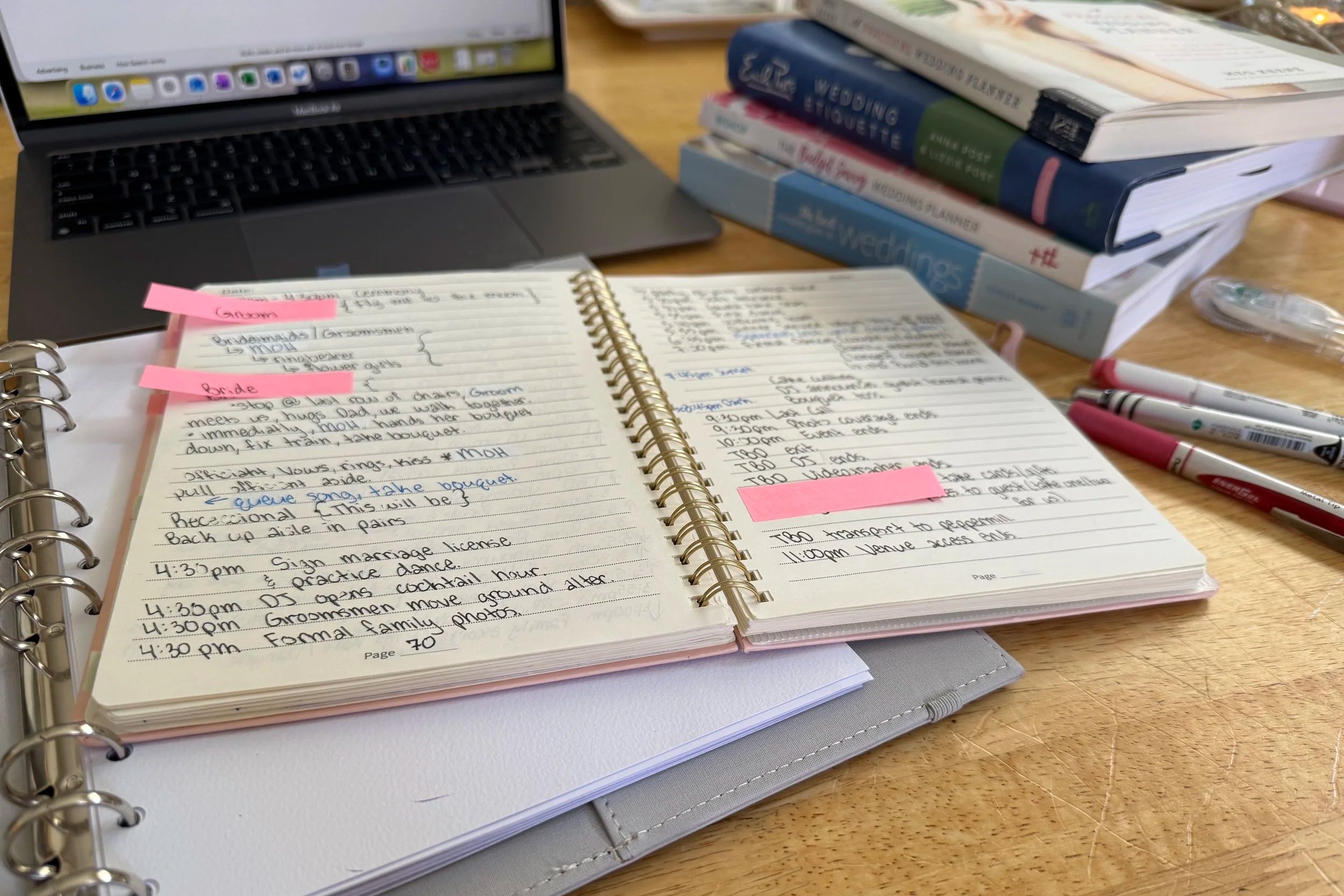 Open wedding planning notebook with wedding day timeline notes, laptop, and planning resources on a table.