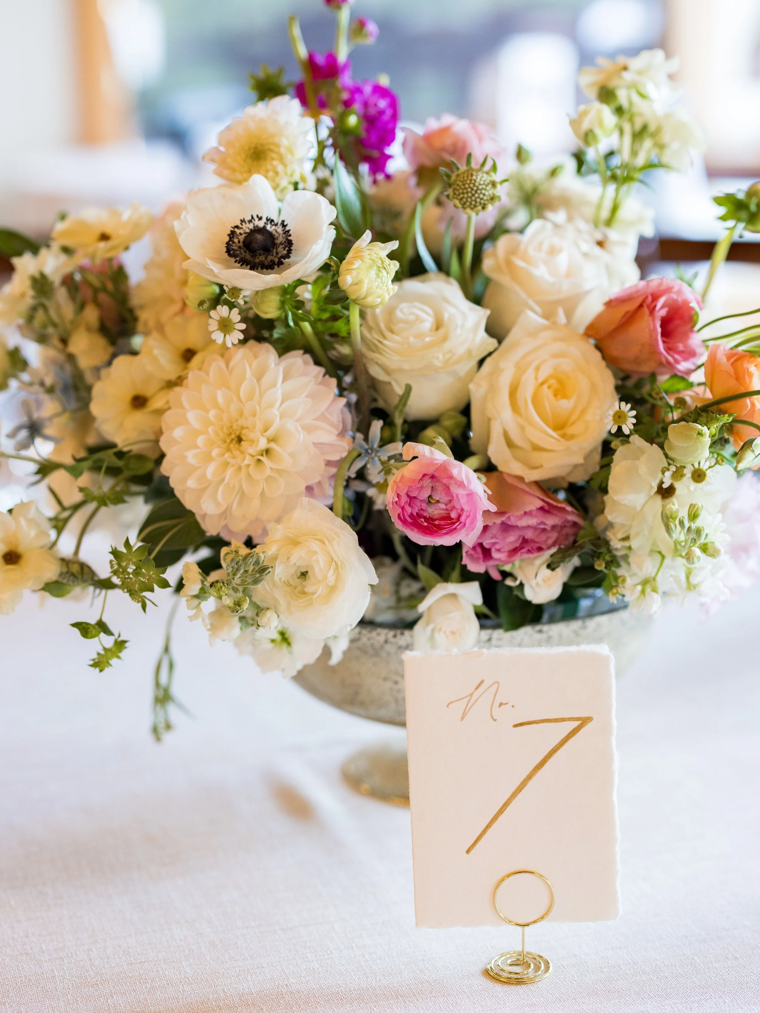 Romantic wedding centerpiece with pastel florals and modern table number styling at an elegant reception.