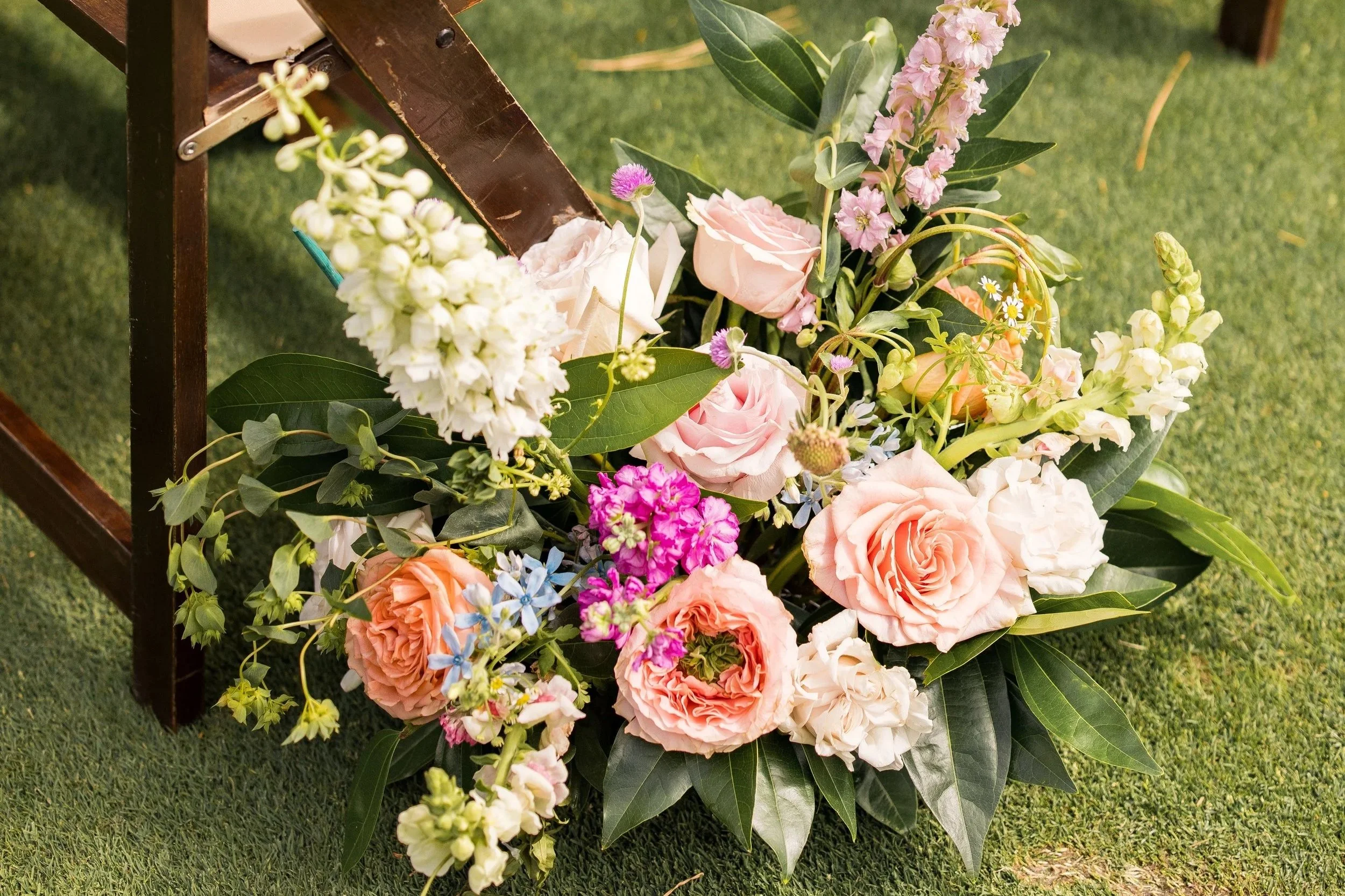 Garden-style ceremony flowers attached to wooden chairs during an outdoor Lake Tahoe wedding ceremony.