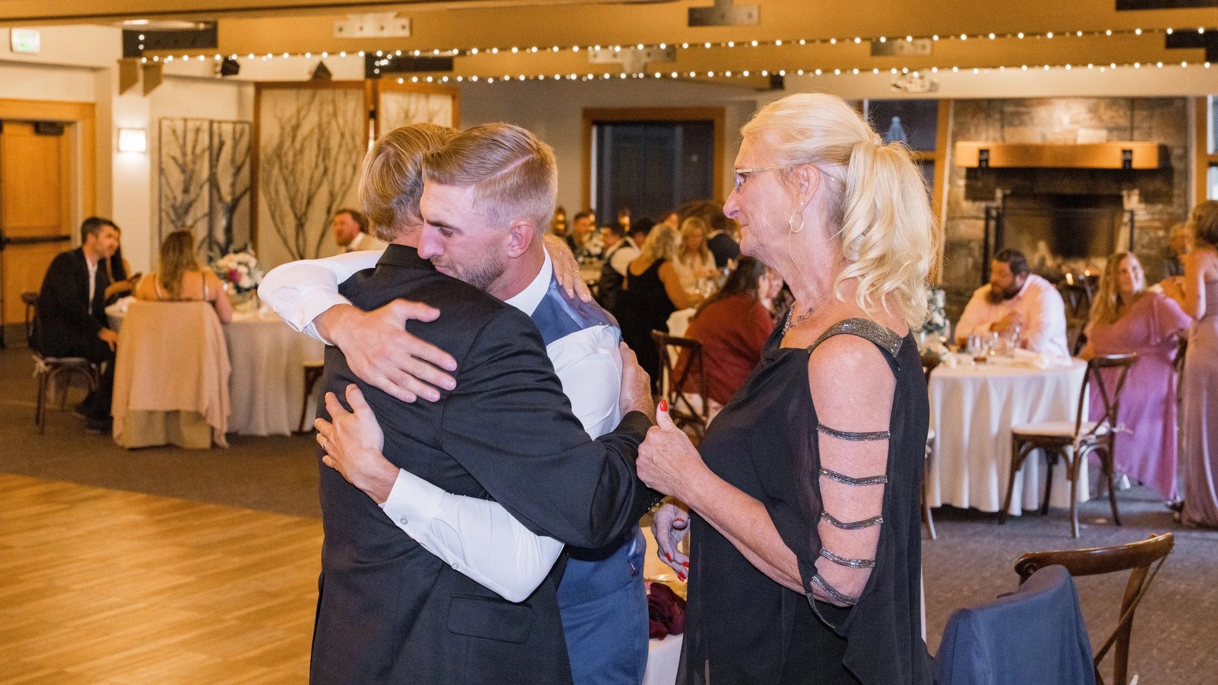 Groom embracing a family member during a wedding reception, illustrating the relationships that make wedding guest list decisions meaningful.