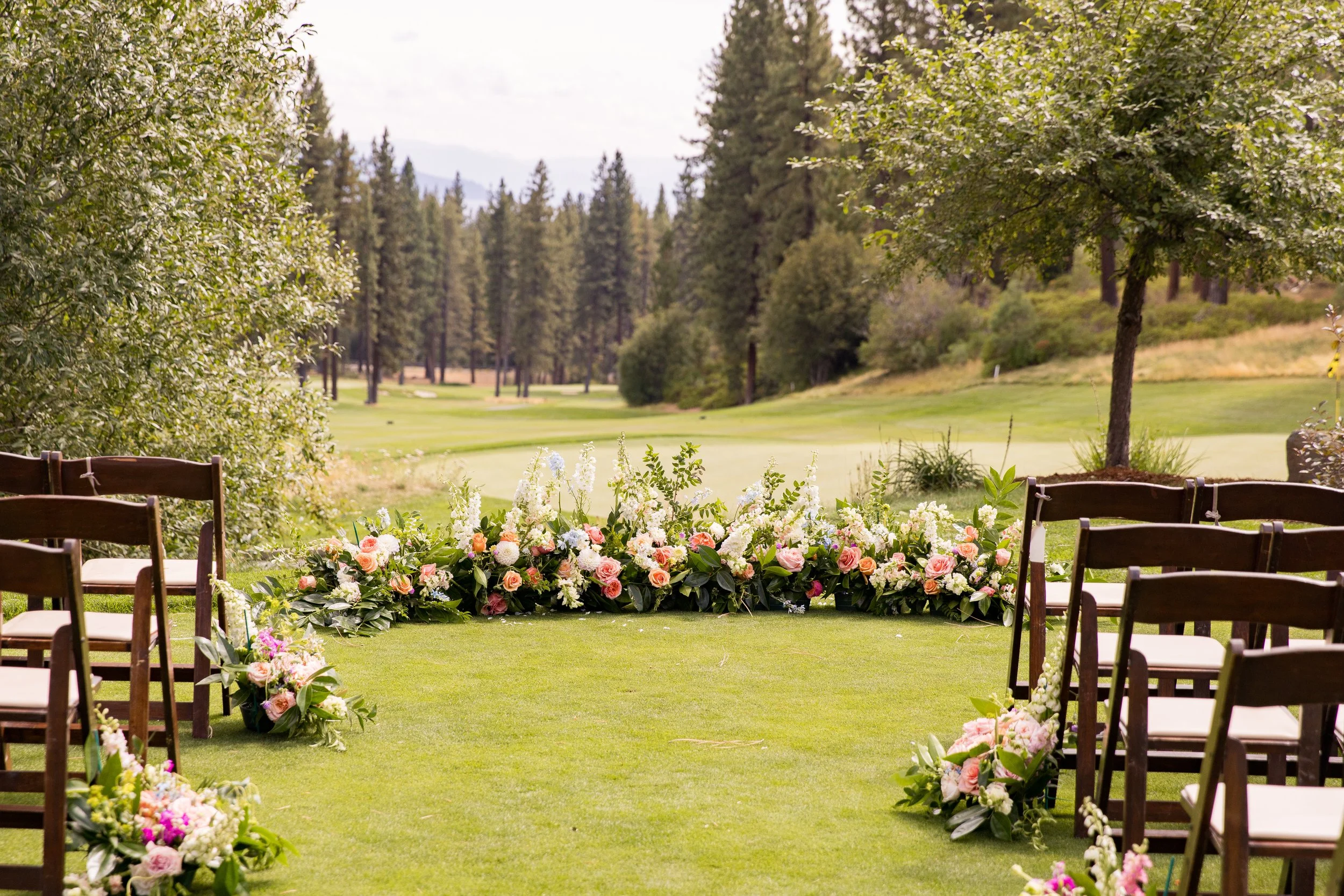 Outdoor wedding ceremony setup with lush floral arrangements at a mountain golf course venue in Northern Nevada.