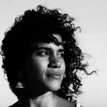 Black and white photo of a woman with curly hair looking to the side.