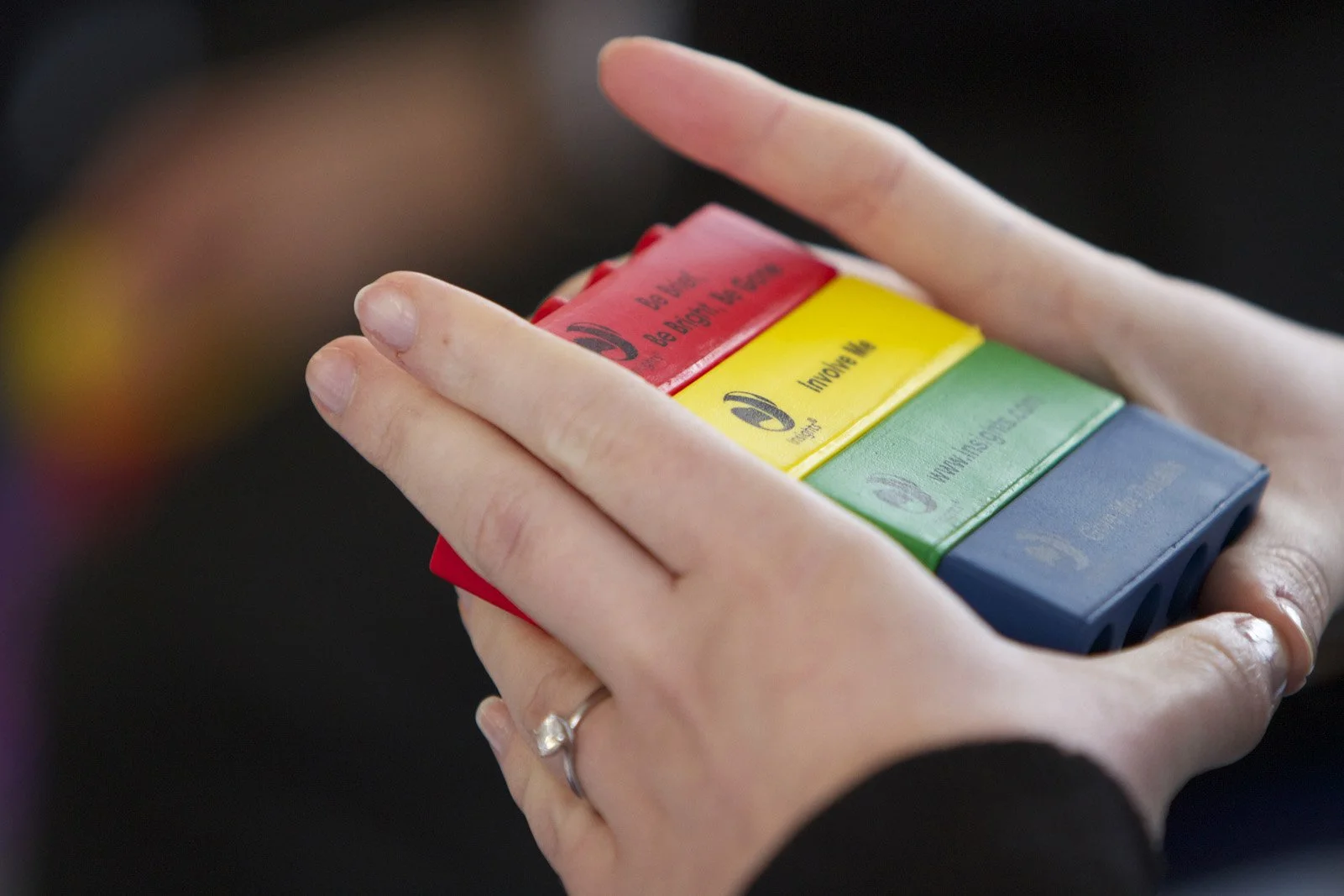 Close-up of a person's hands holding a stack of four coloured blocks in red, yellow, green, and blue colours.