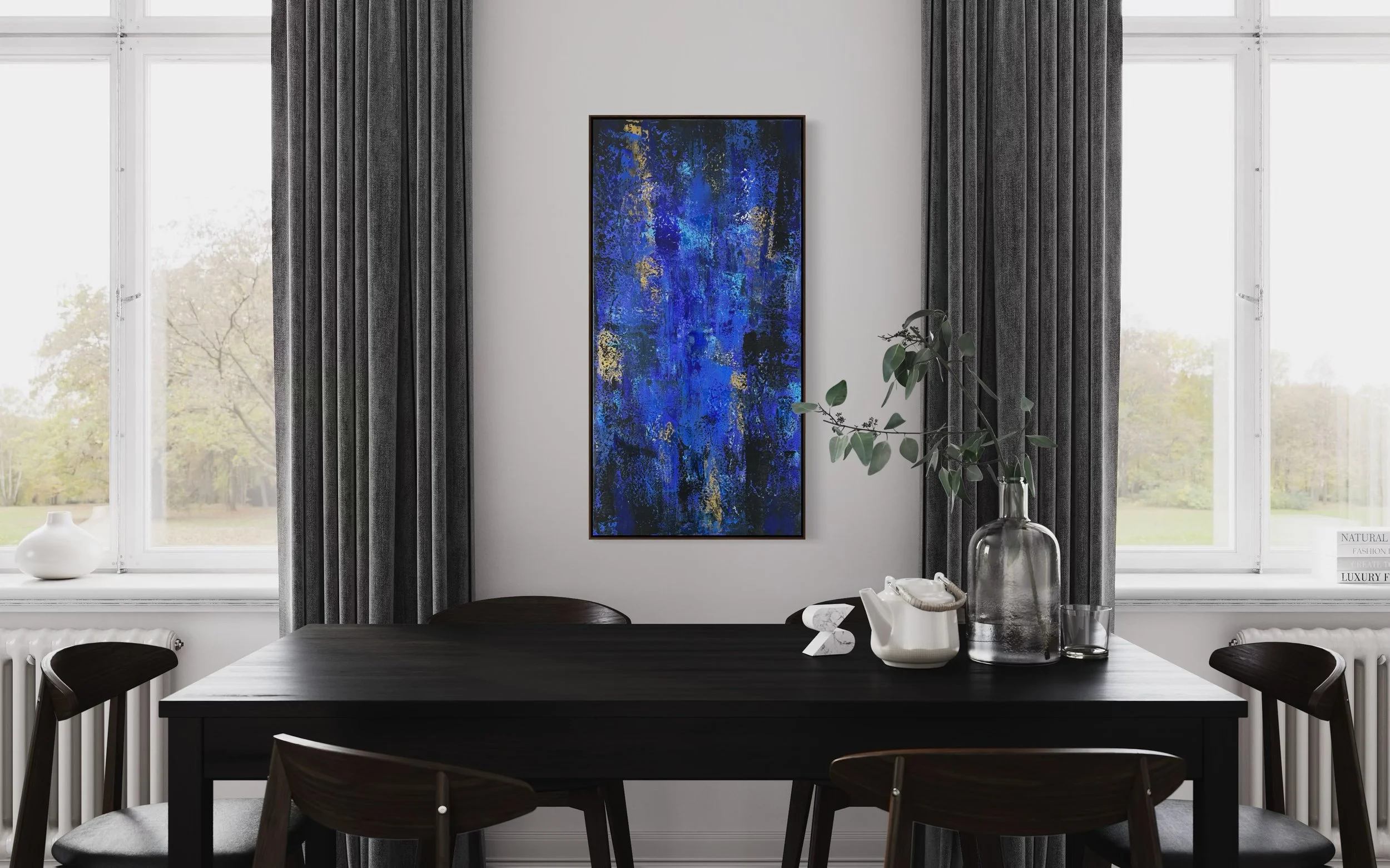 Salle à manger avec table noire, chaises en bois, grande fenêtre avec rideaux gris, œuvres d'art bleues, vase avec des feuilles, objets décoratifs sur la table, paysage extérieur visible.