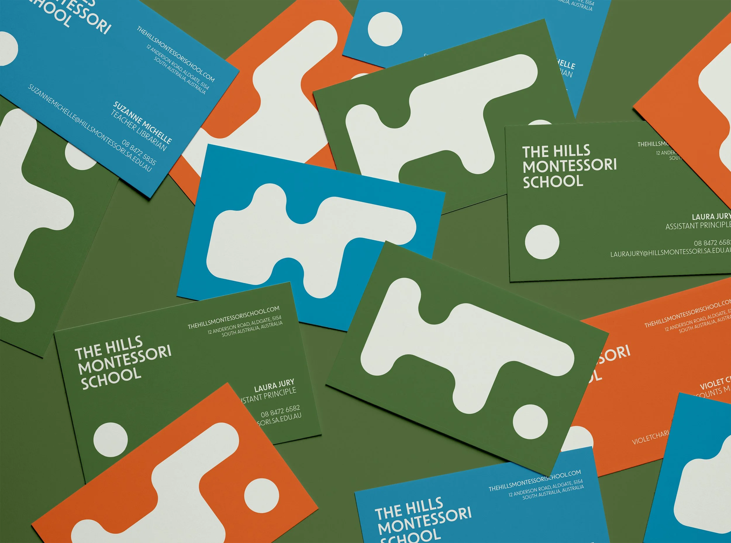 A collection of business cards for The Hills Montessori School in green, blue, and orange colors, featuring the school's name, contact information, and an abstract white logo.