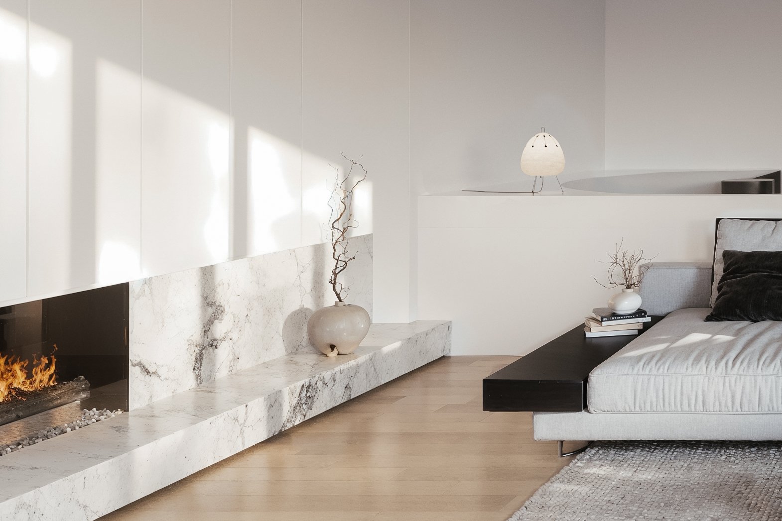 Modern living room with a sleek fireplace, minimalistic decor, a light-colored sofa with dark pillows, and a few decorative items like vases and books.