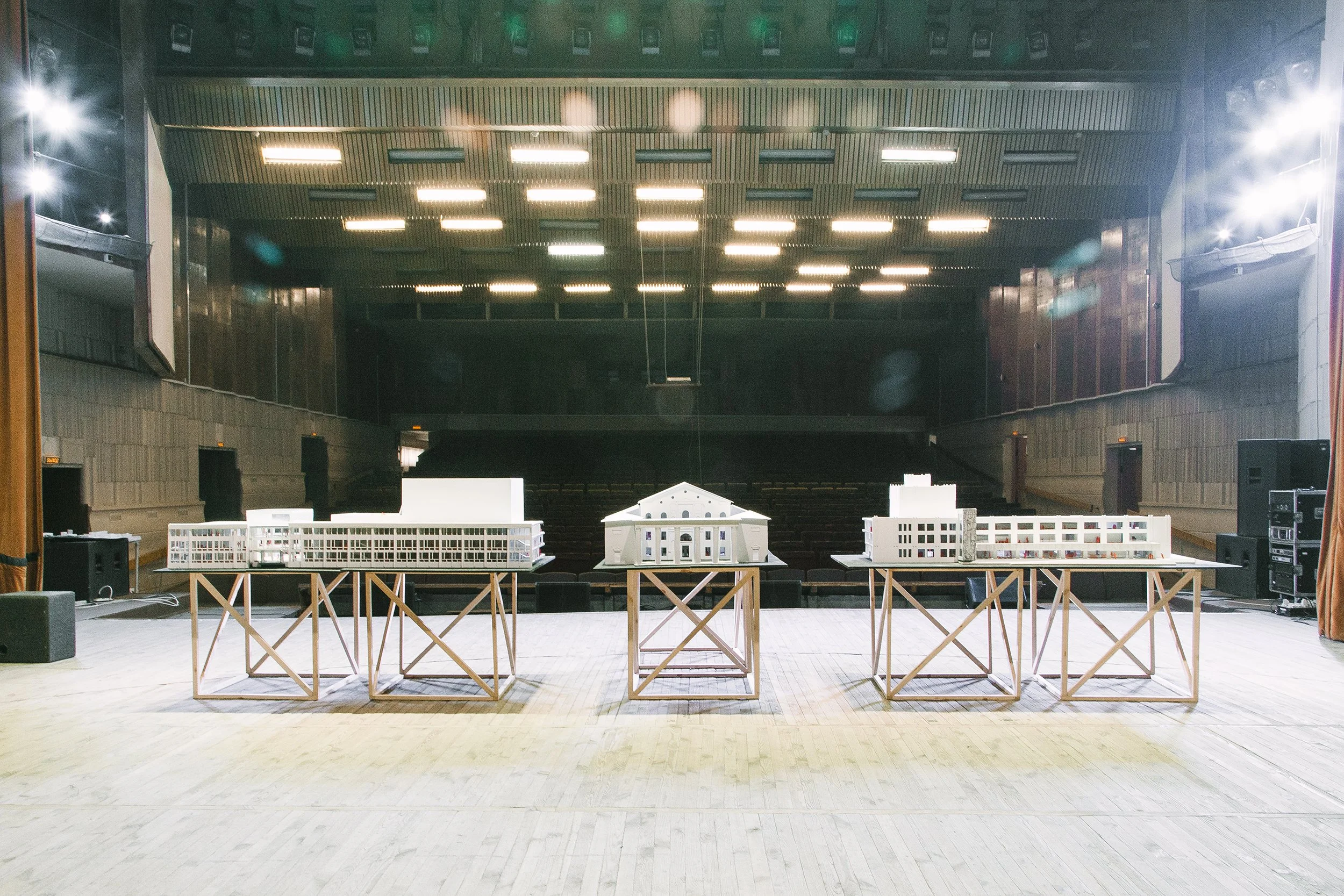Empty auditorium with stage and architectural models displayed on tables.