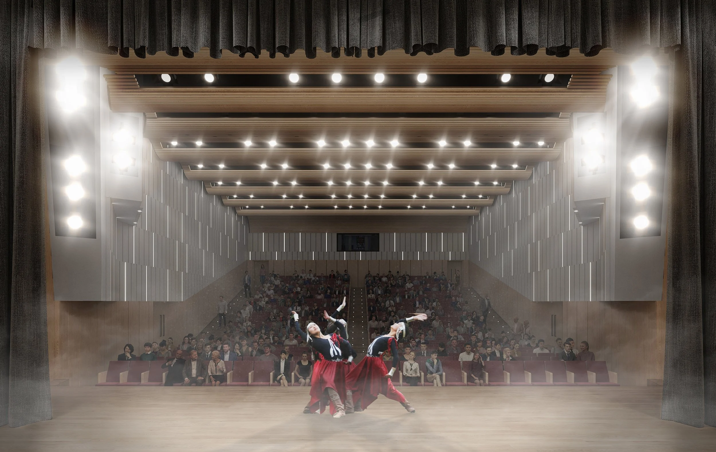 A dance troupe performs on stage in front of an audience in a modern theater with ceiling lights and audience seating.