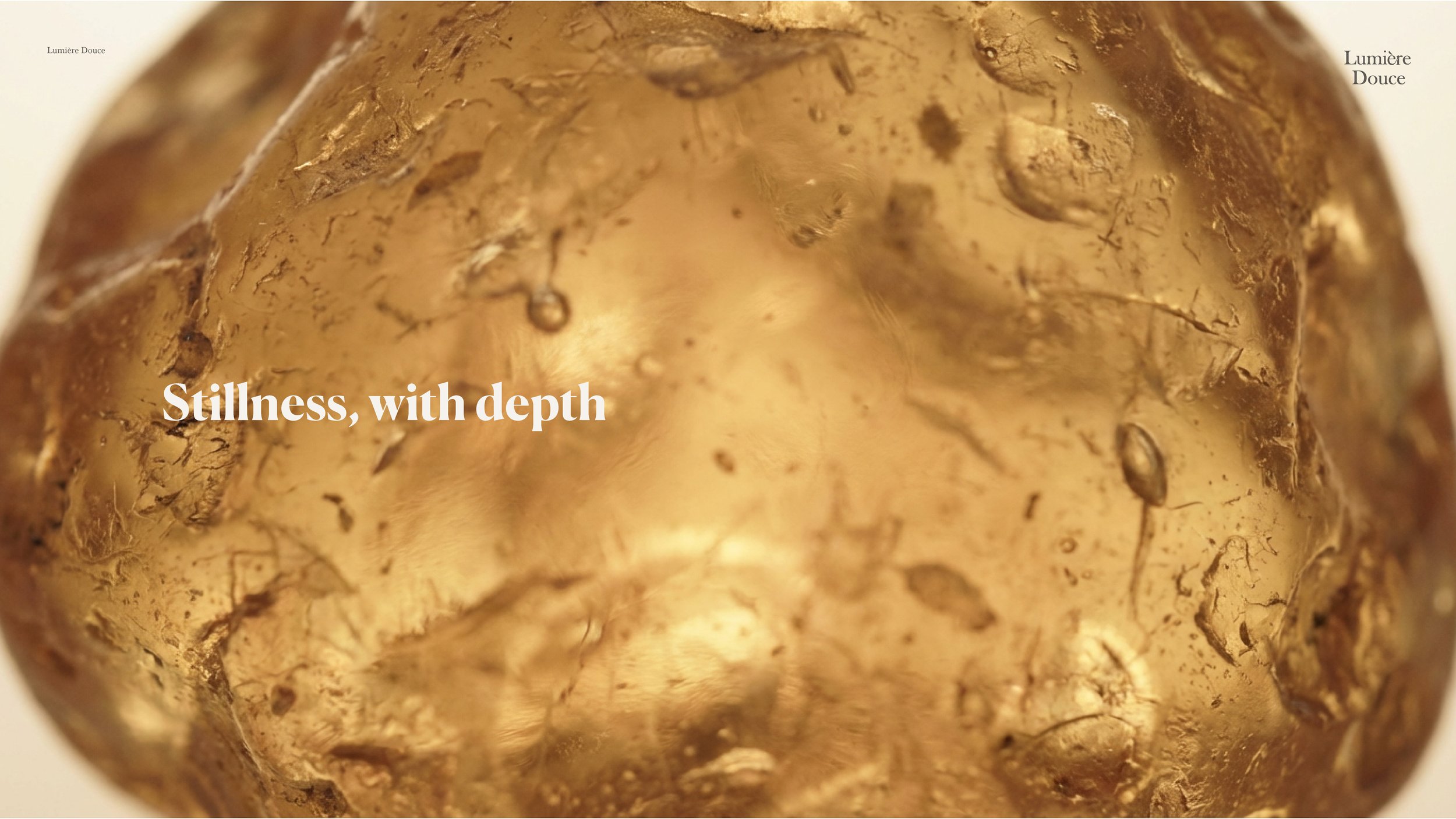 Close-up of a gold, textured, and glossy decorative object with the words 'Stillness, with depth' overlaid in white text.