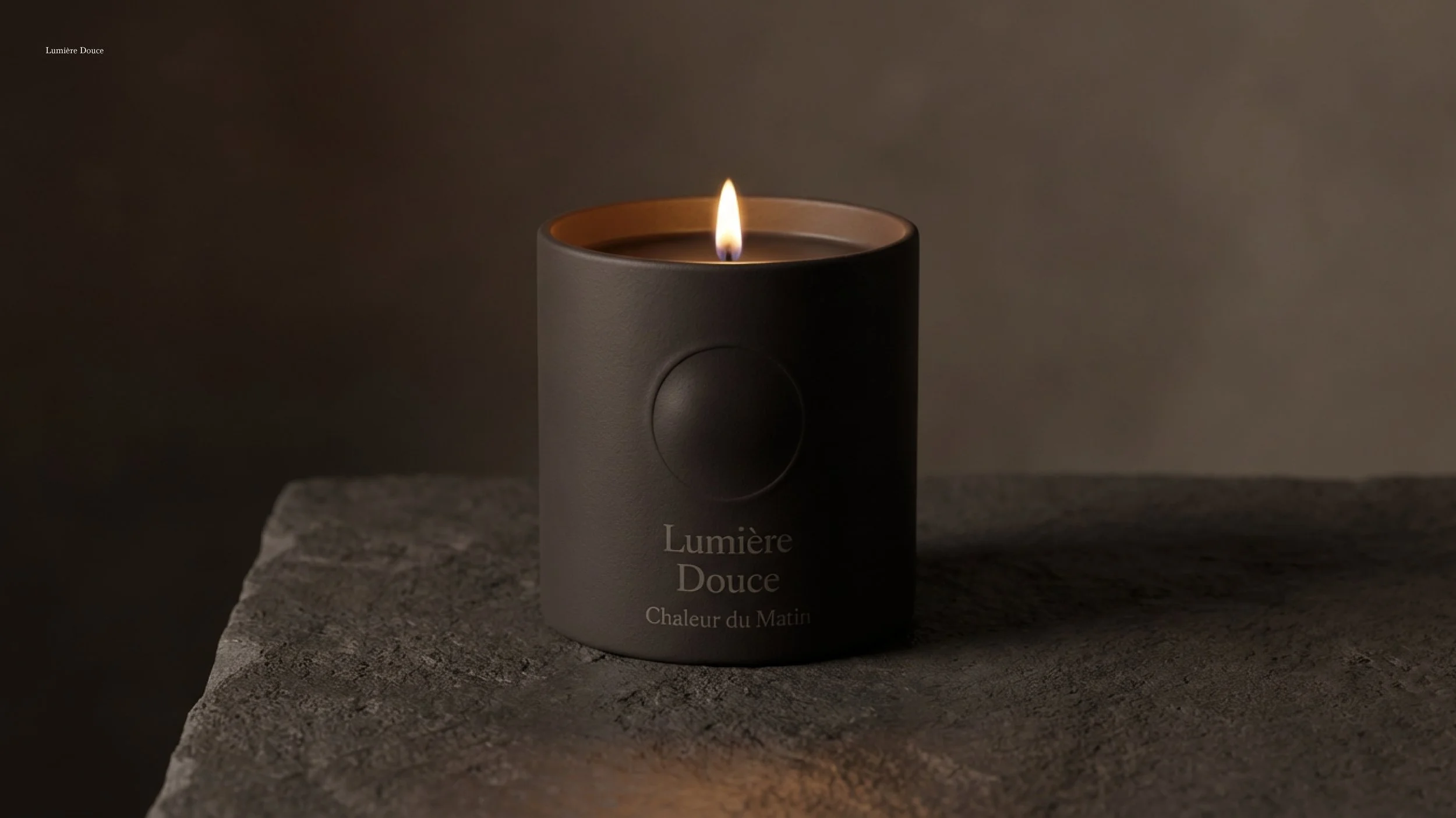 A black candle with a lit flame sitting on a textured stone surface, with a smooth, brown, gradient background.