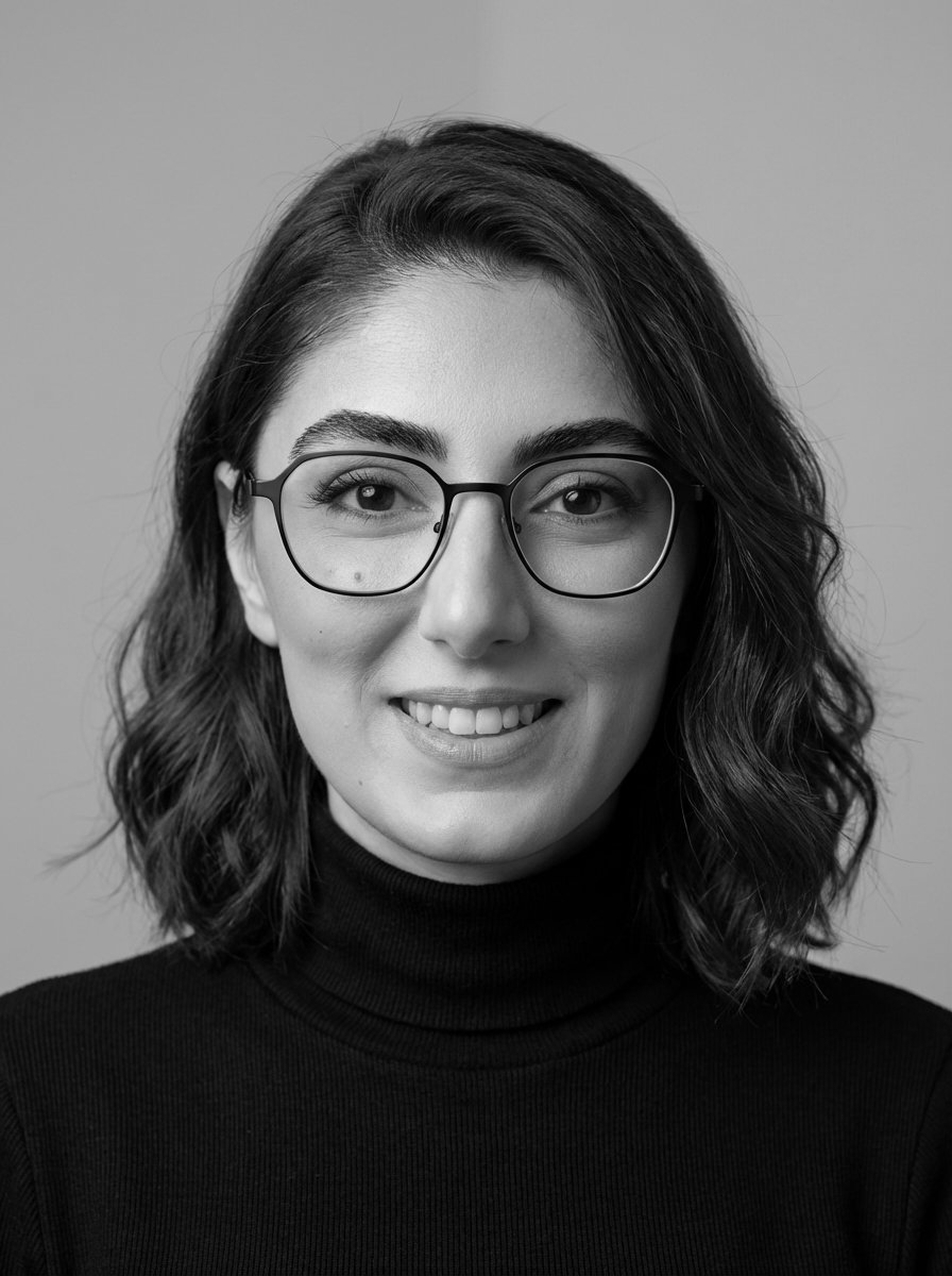 Black and white portrait of a Niloofar with wavy hair, glasses, and a black turtleneck, smiling at the camera.