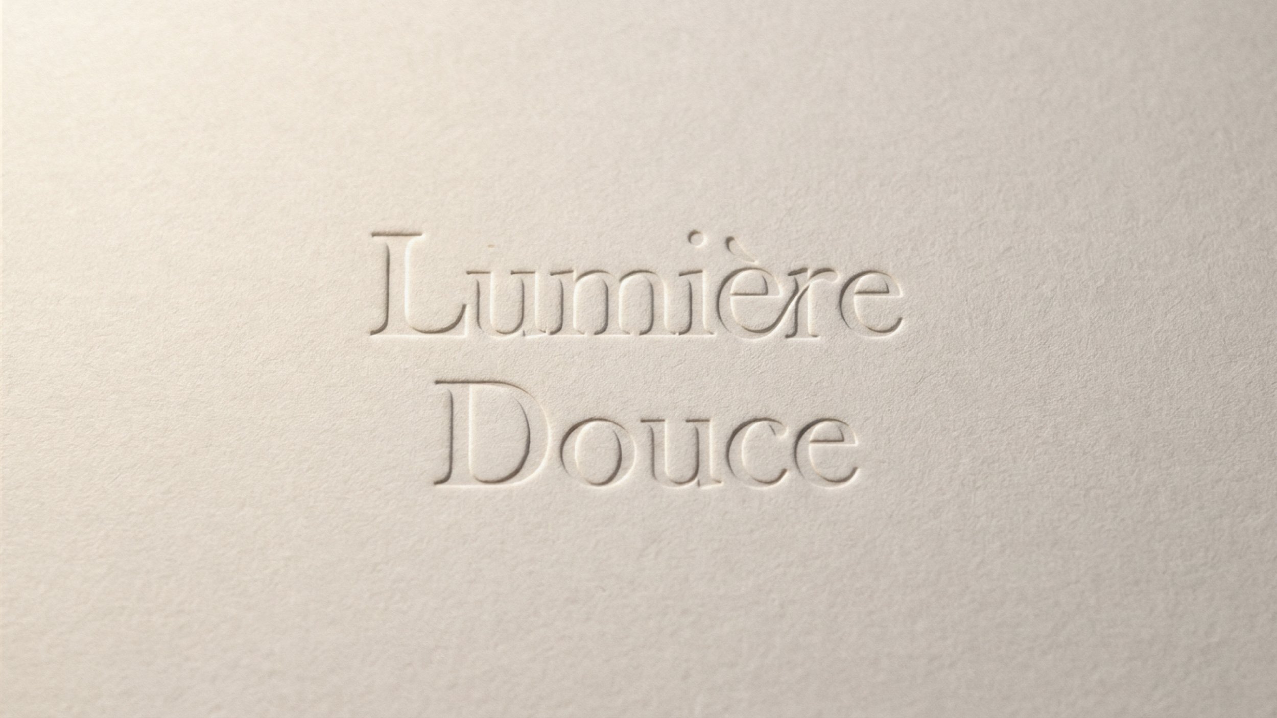 Embossed text on a cream-colored surface that reads 'Lumière Douce'.
