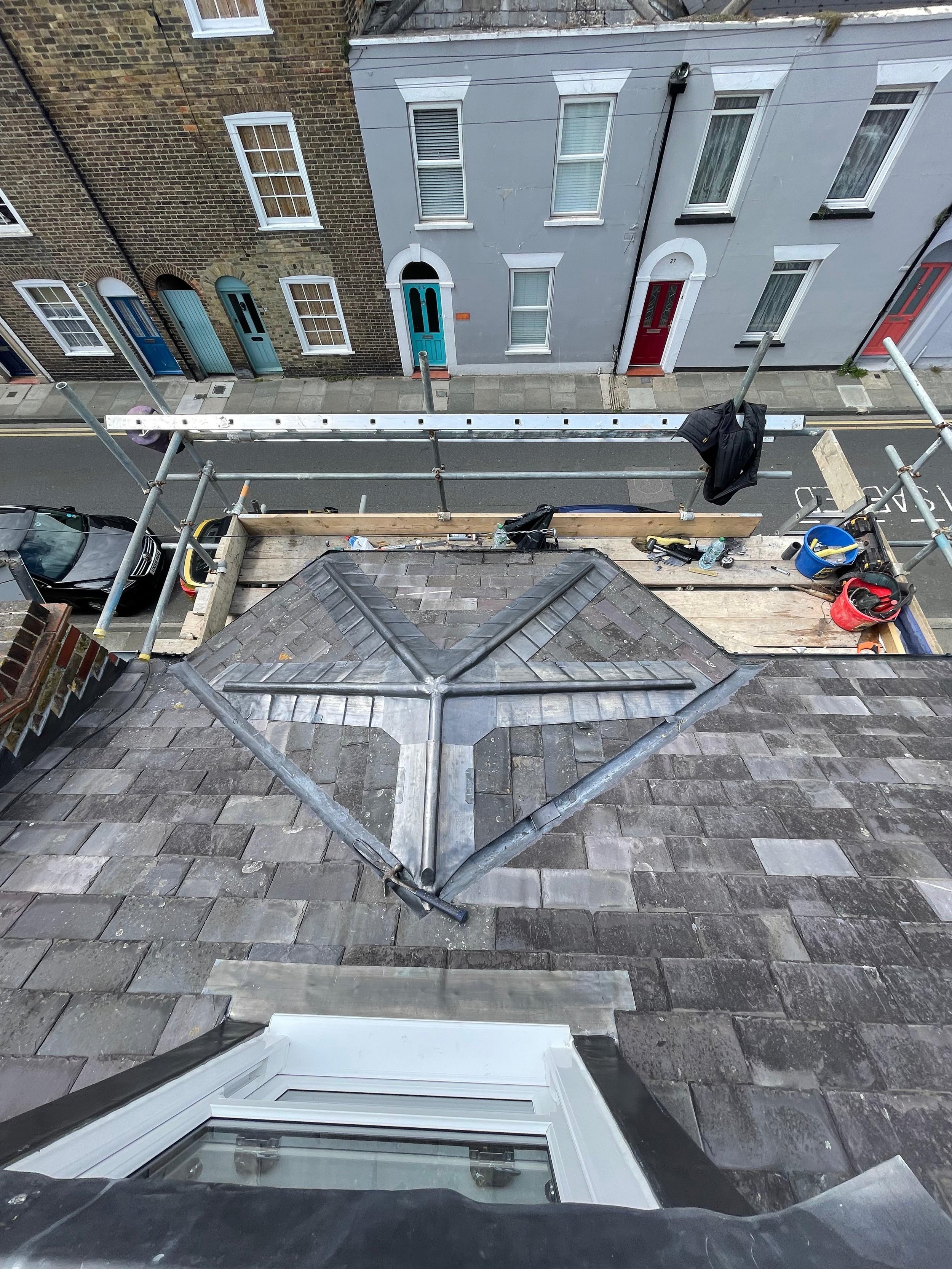 View from a rooftop under construction, showing scaffolding, items, and a section of the roof with roofing materials.