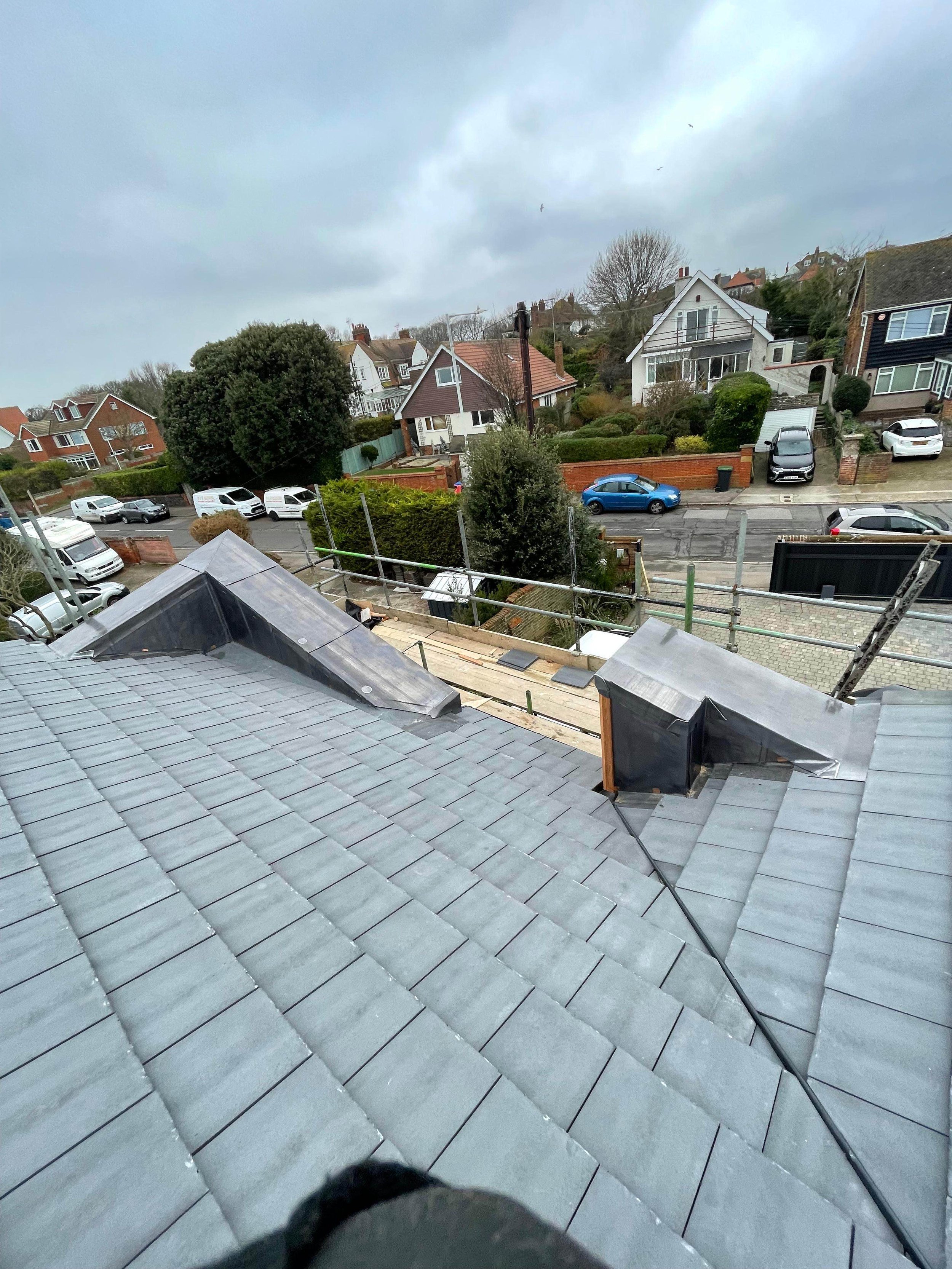 View from a rooftop looking at neighboring houses and streets on a cloudy day.