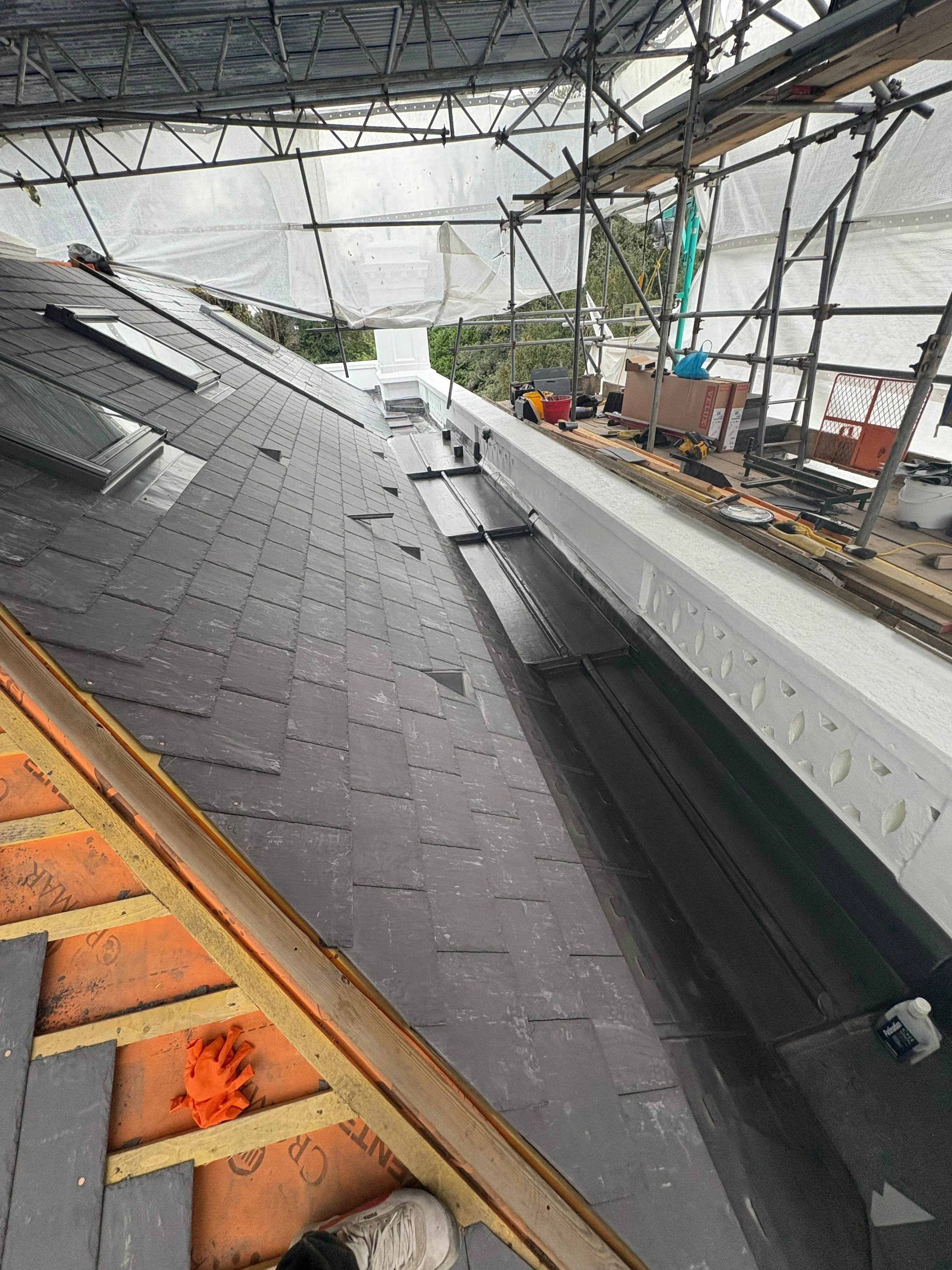 Construction scaffolding and tools on a roof under repair, with roofing materials and equipment visible.