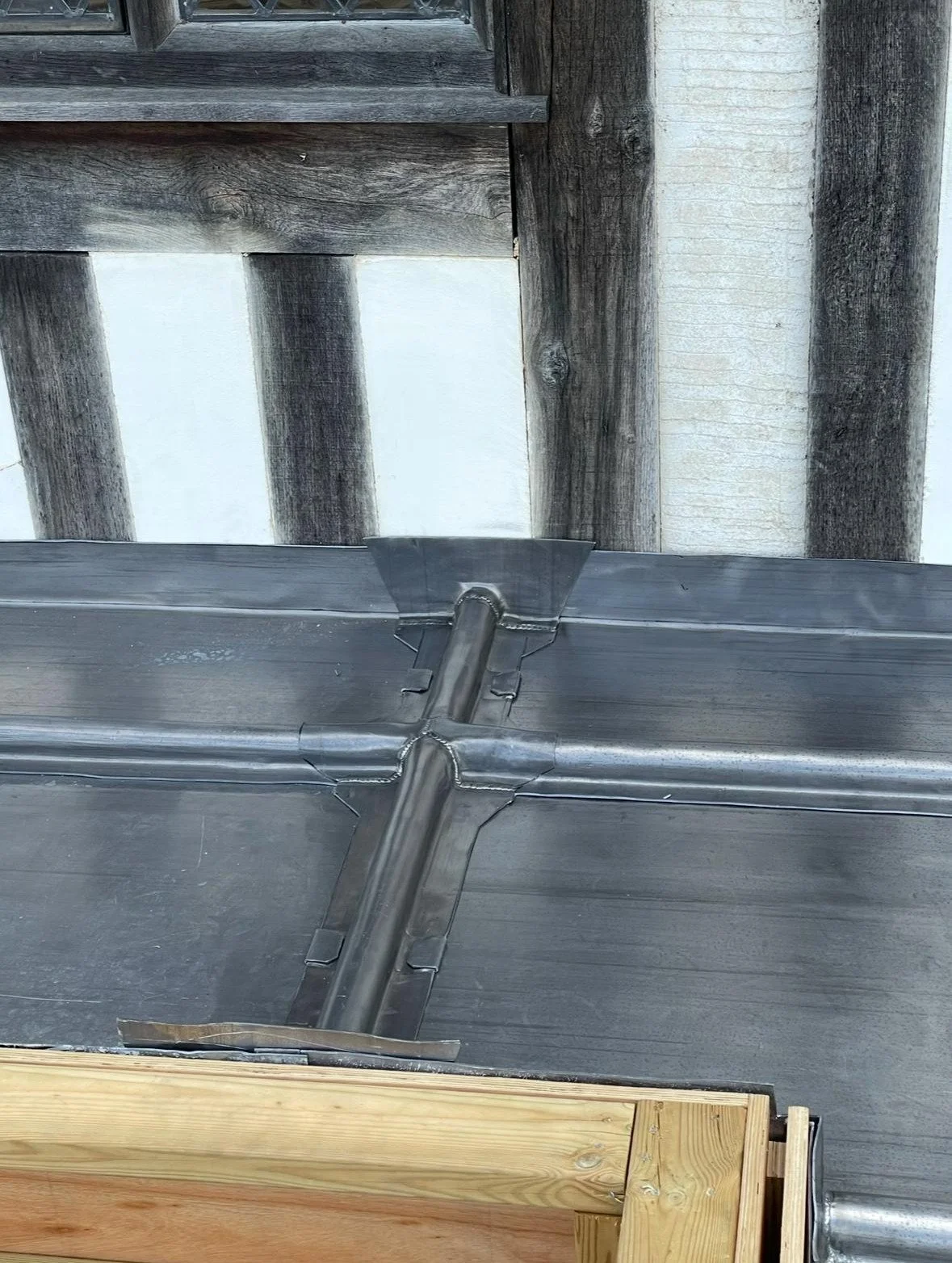 Metal ductwork and a wooden support in a construction or renovation setting.