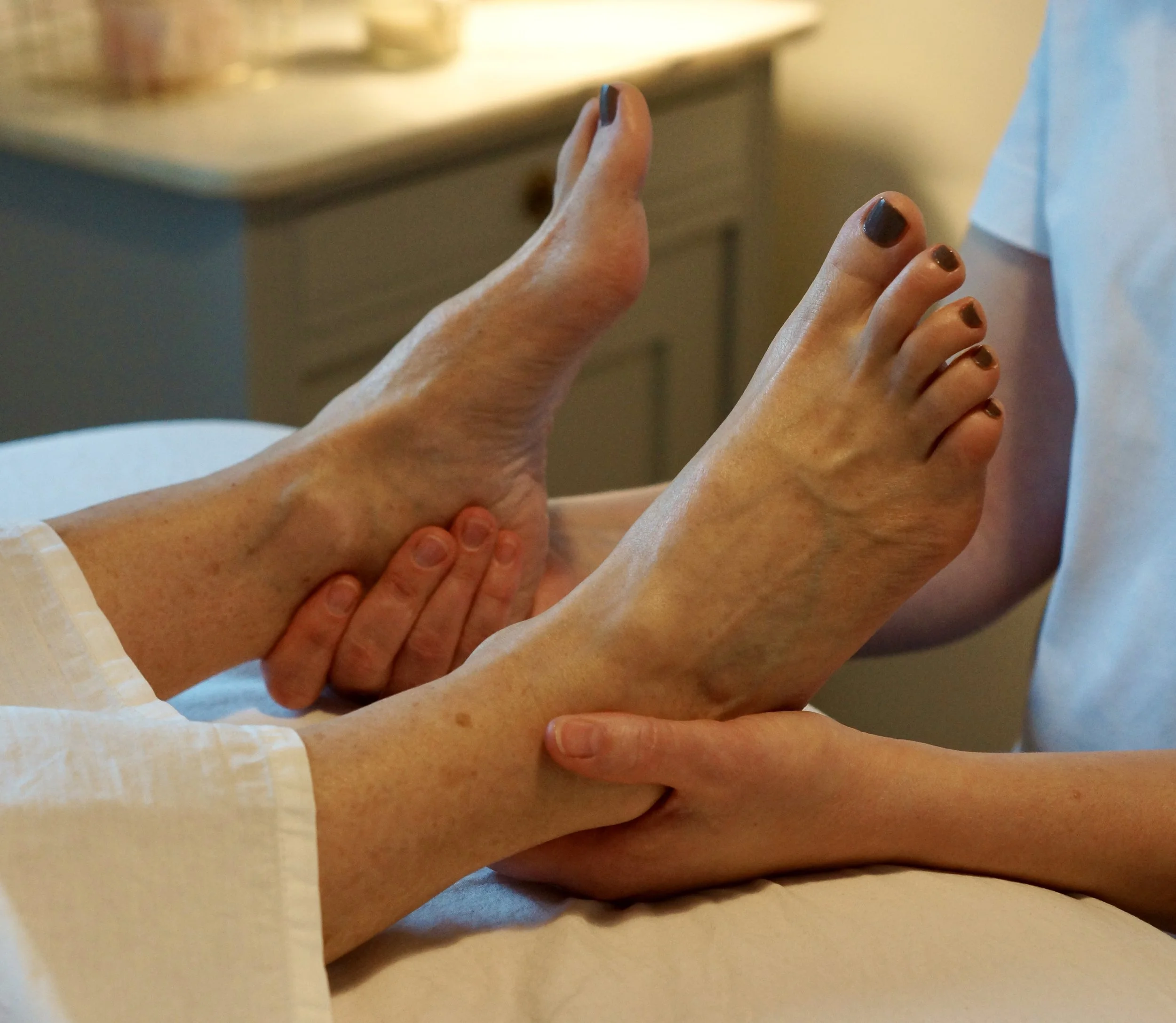 Person receiving a foot massage from a therapist in a spa or wellness setting.