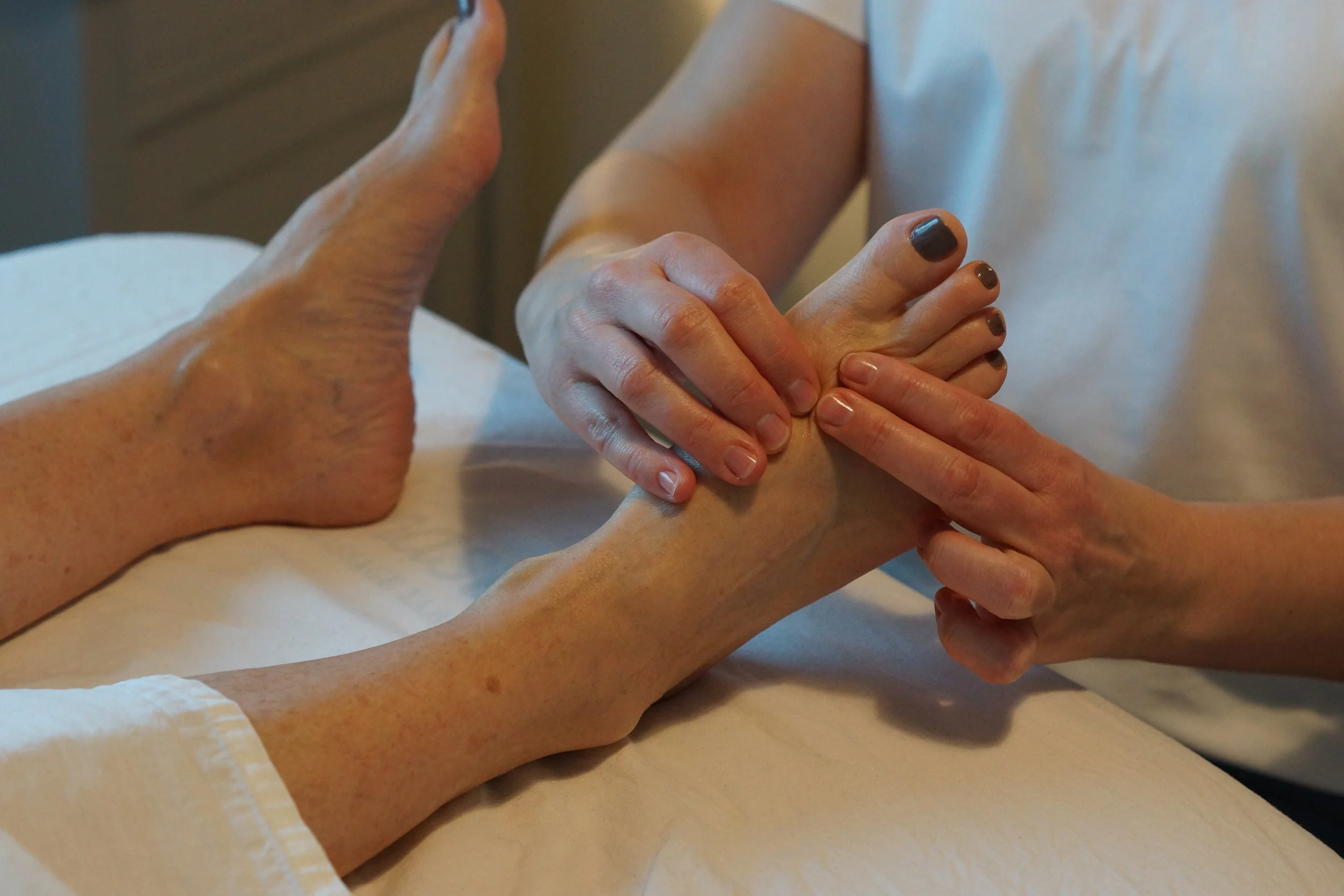 A person receiving a massage on their arm from a massage therapist in a well-lit room.