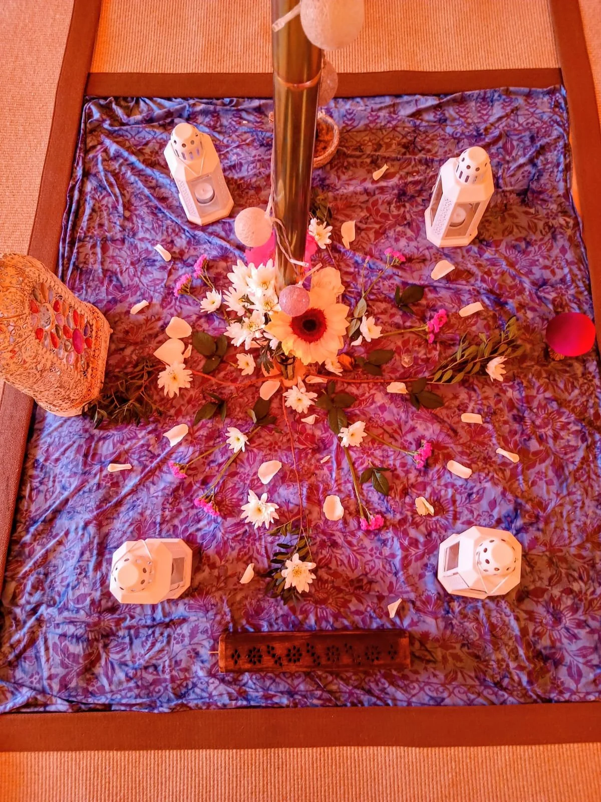 A decorated altar with flowers, candles, and lanterns, with a pink hue overall.