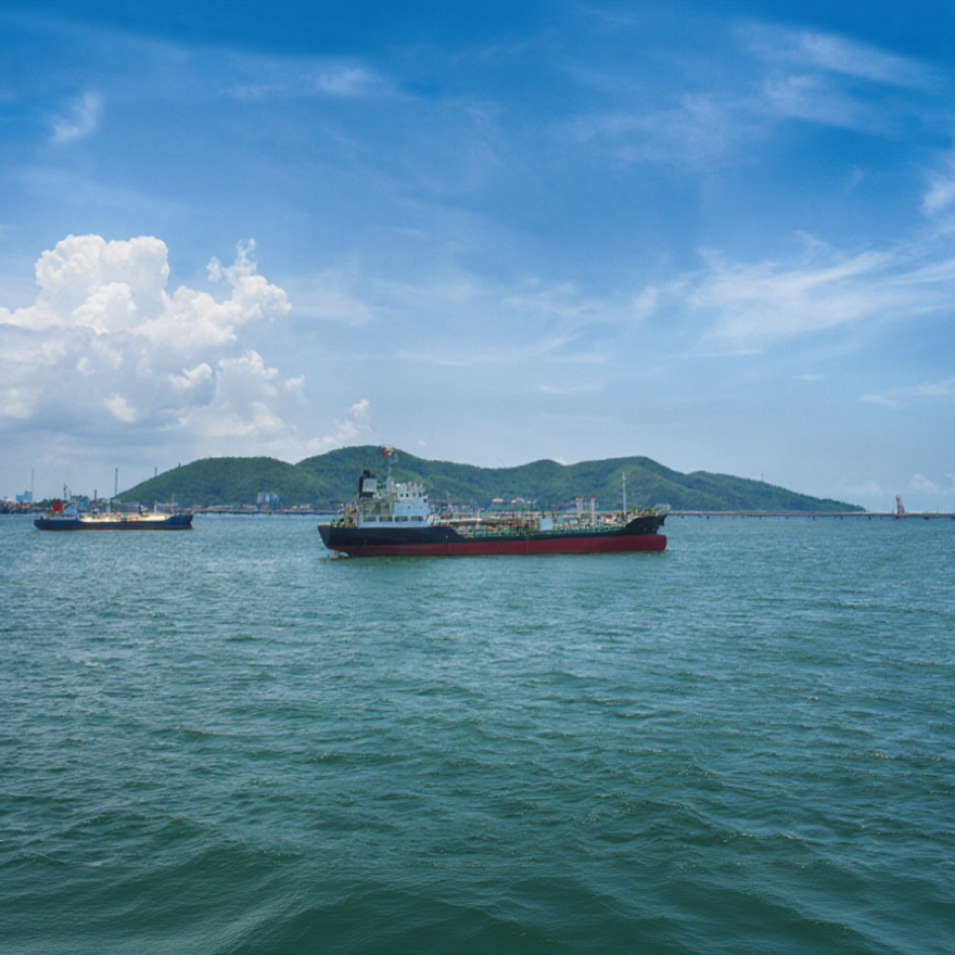 Ships on the water with a hilly landscape in the background under a partly cloudy sky.
