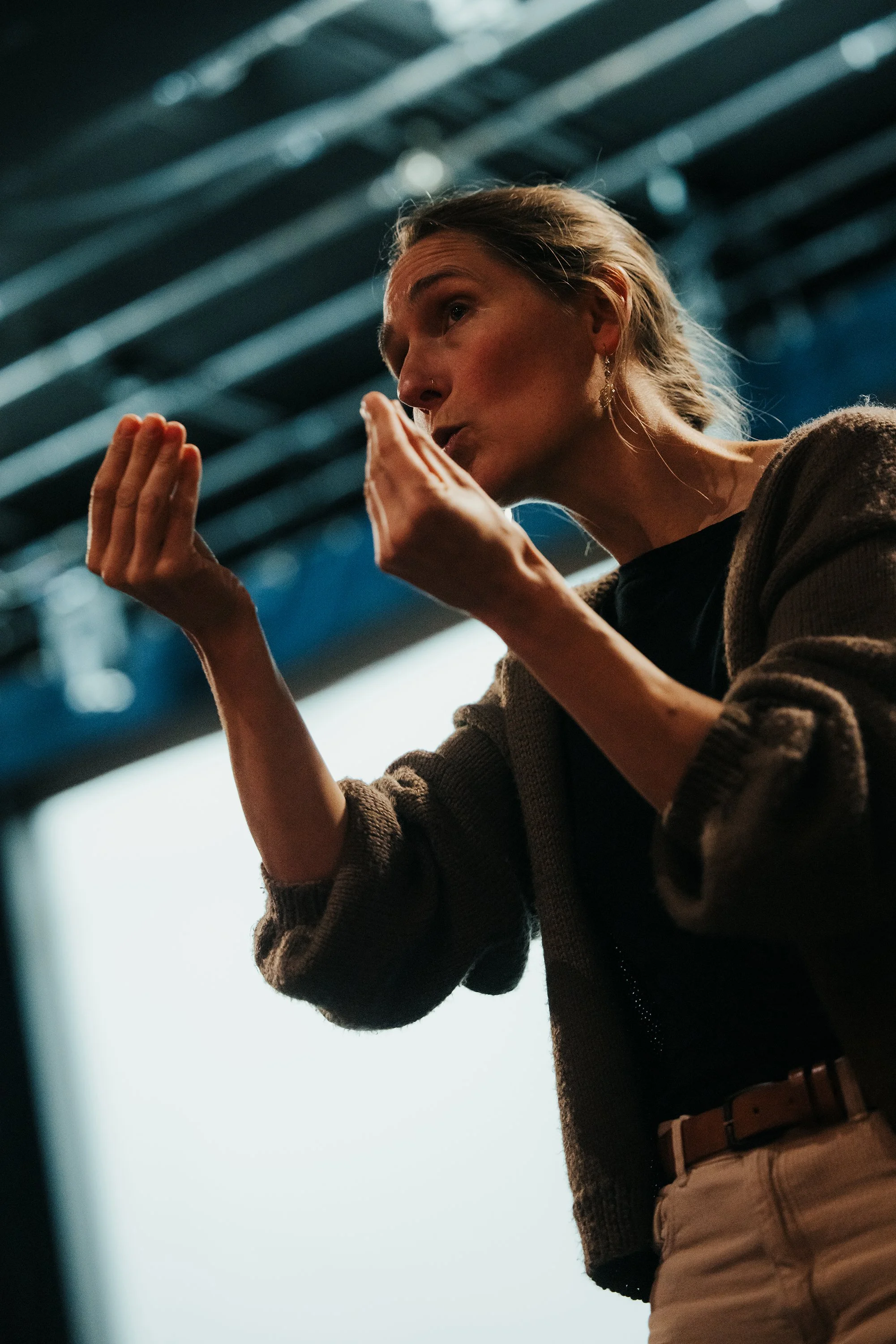Une femme parlant et gesticulant lors d'une présentation ou d'une discussion, dans un cinéma.