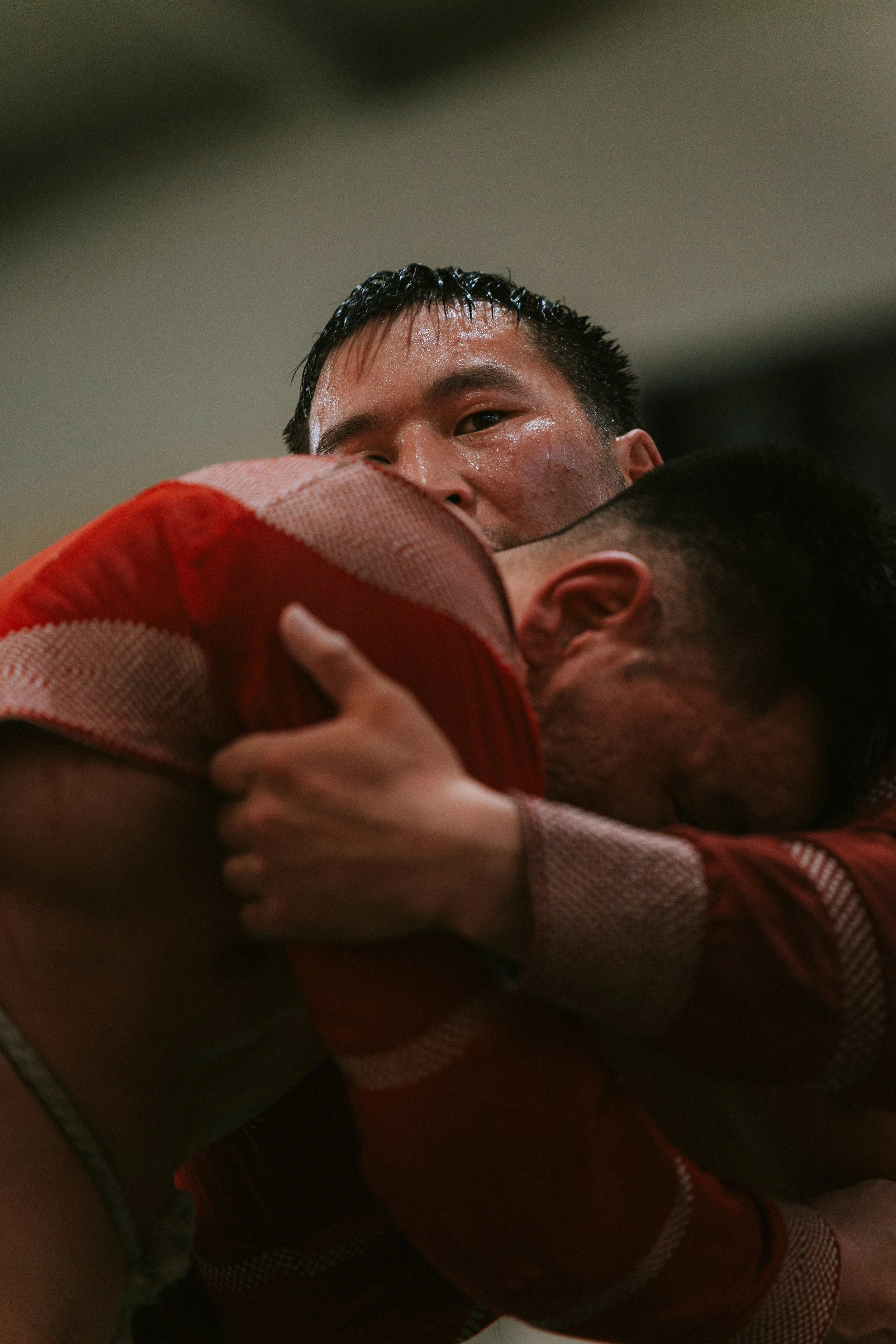 Deux joueurs de football en sueur s'embrassent en pleurant, manifestant leur victoire ou leur émotion intense.