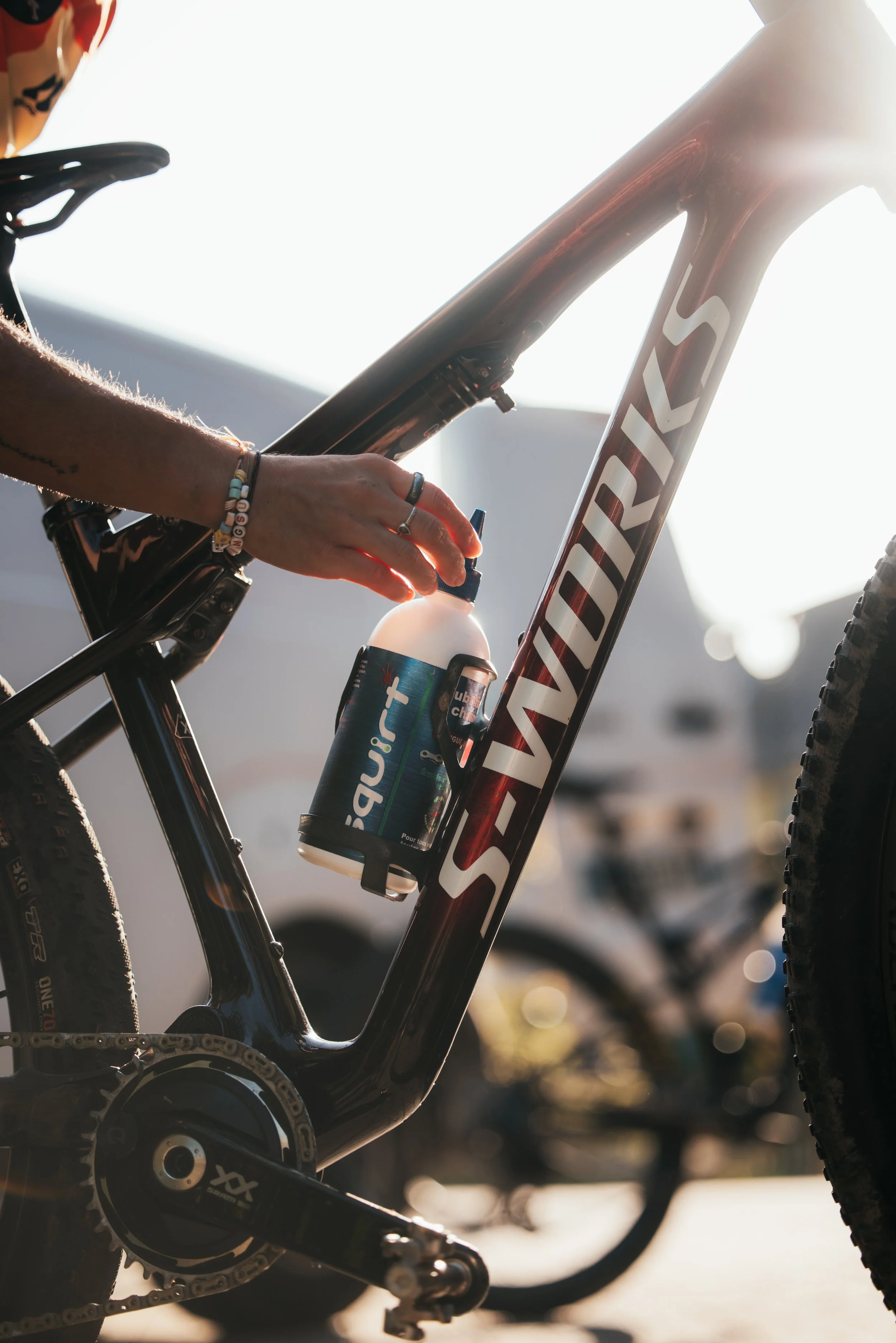 Un vélo de montagne noir avec le mot 'VANQUEST' écrit dessus, avec une personne en train d'ajouter de l'eau dans une bouteille attachée au cadre du vélo.