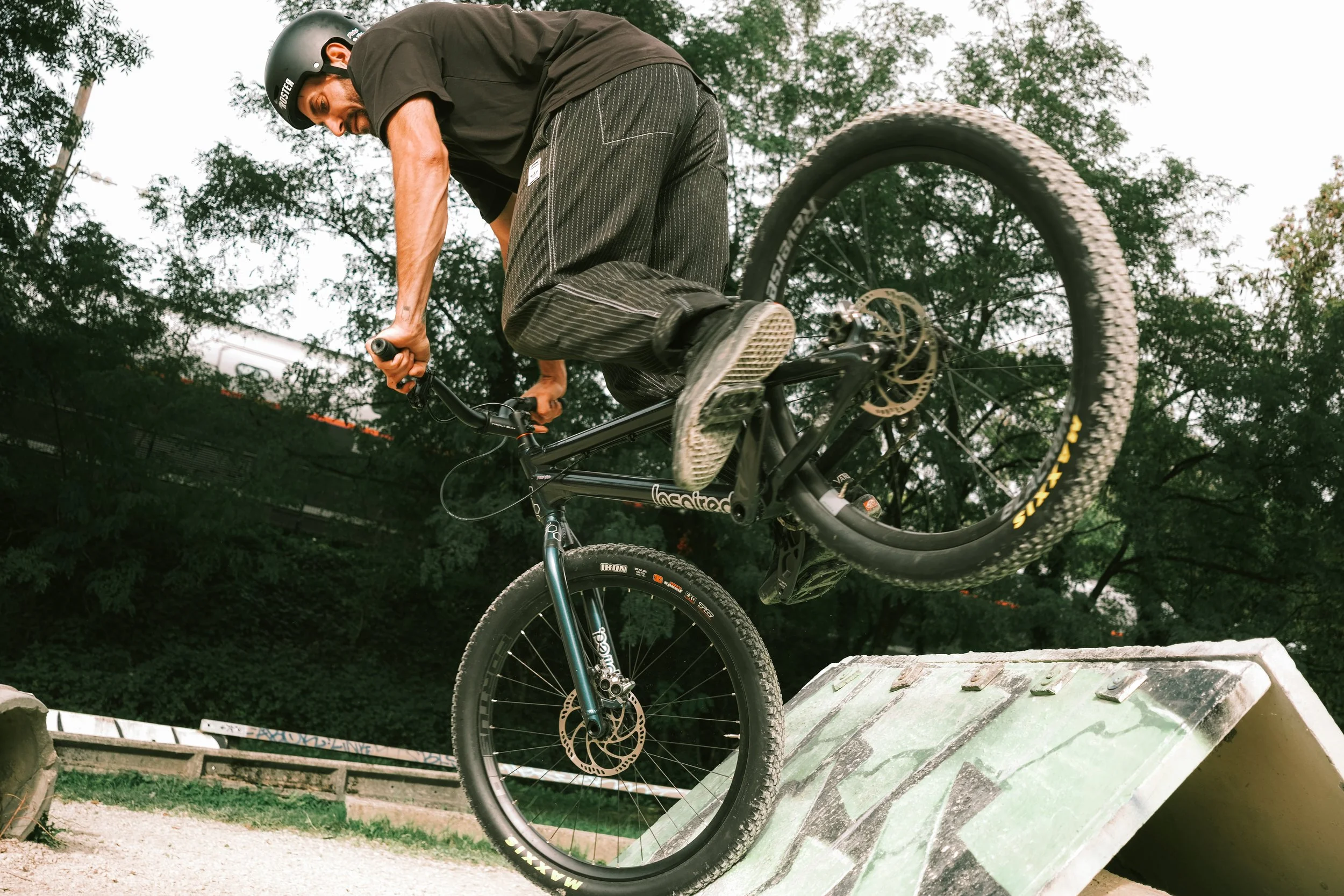 Un bmx en casque effectue un saut sur un obstacle dans un parc de vélo tout-terrain.