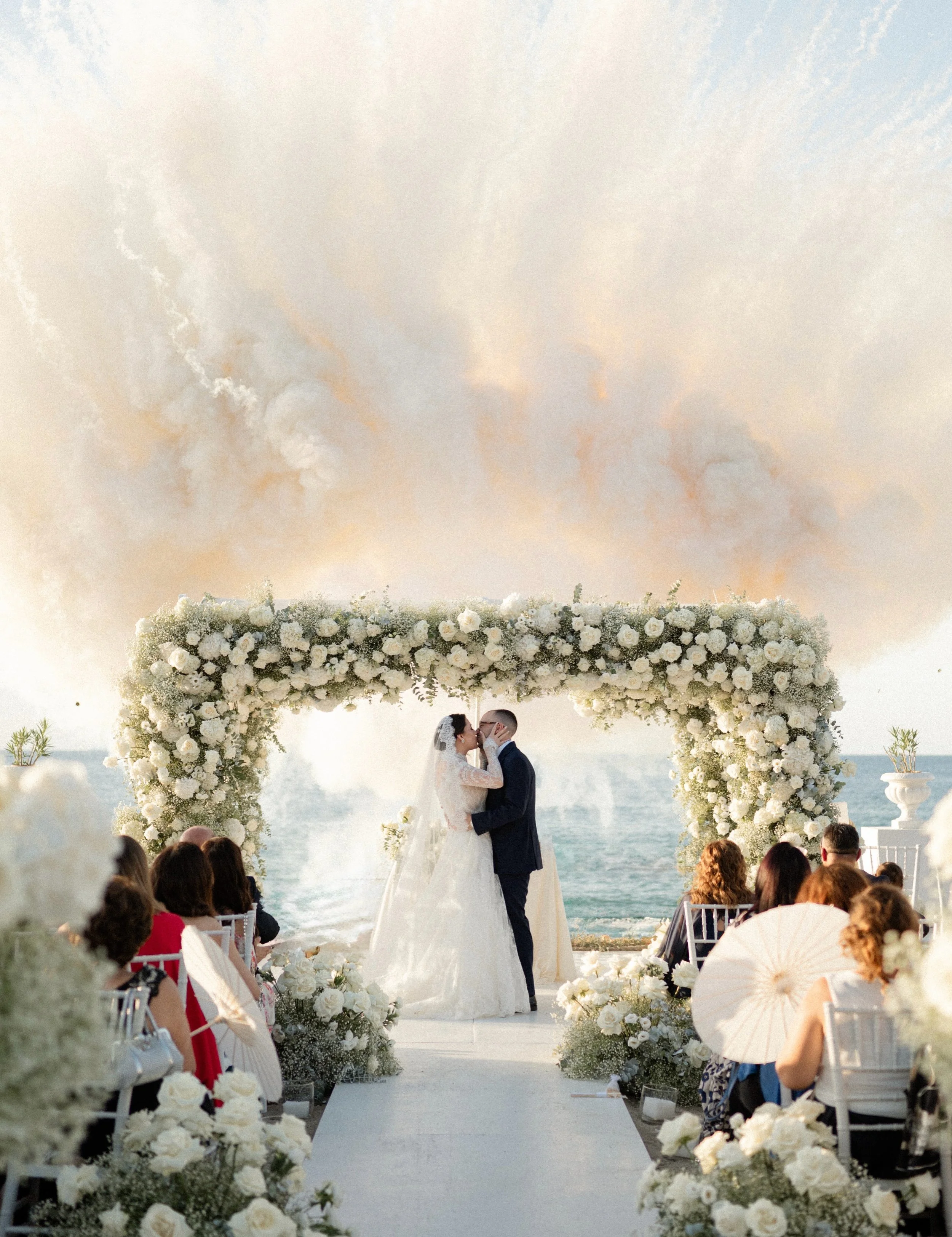 White roses against an endless blue. A sea breeze lifting her veil. And the joy of walking back down the aisle, hand in hand.

Antonio &amp; Luisa&rsquo;s wedding unfolded in a setting where every detail belonged: abundant white blooms, delicate text