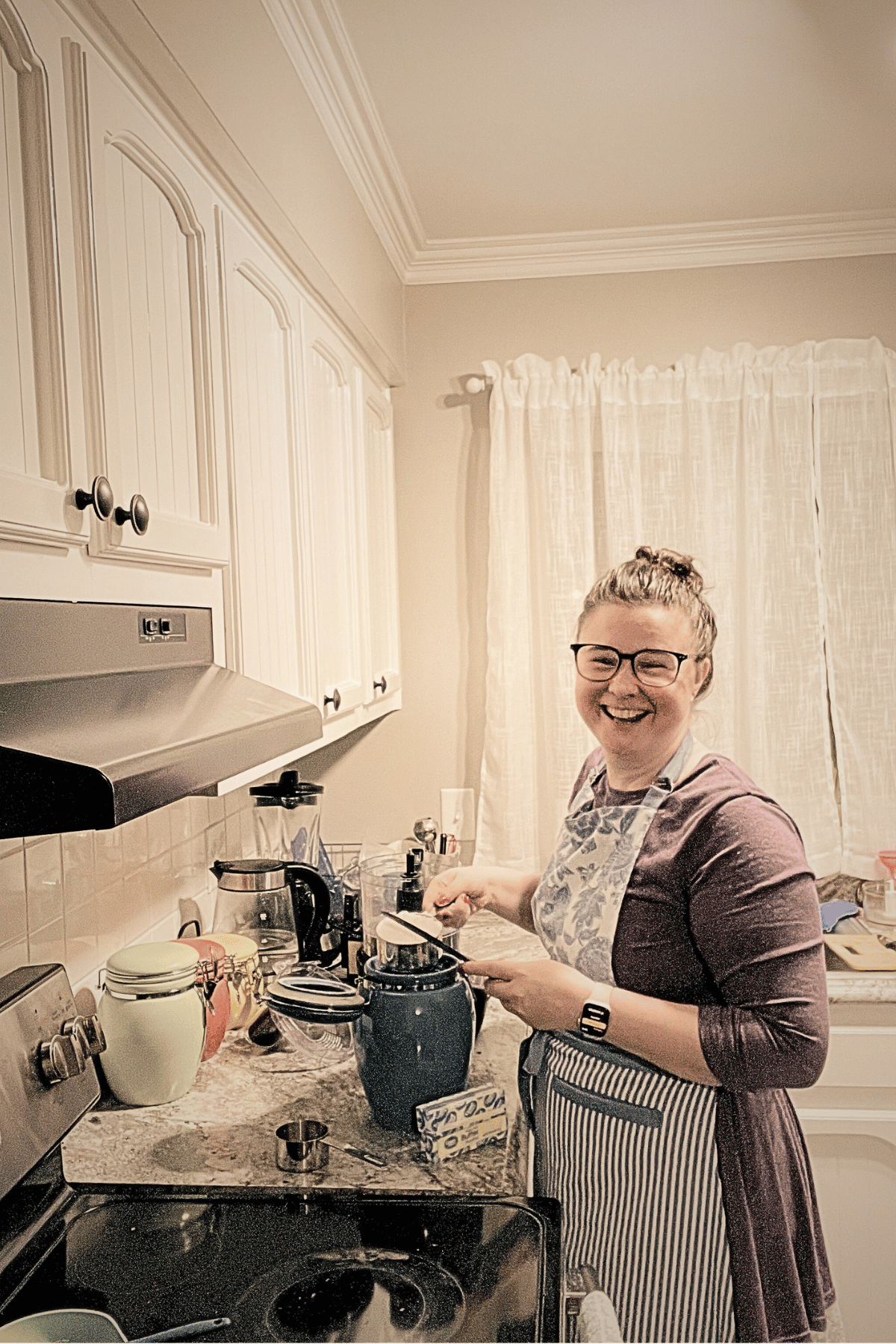 Cathlyn of Merry Berry Confection Co. in Cary, NC, wears a blue flowered apron and measures a cup of flour, smiling at the camera.