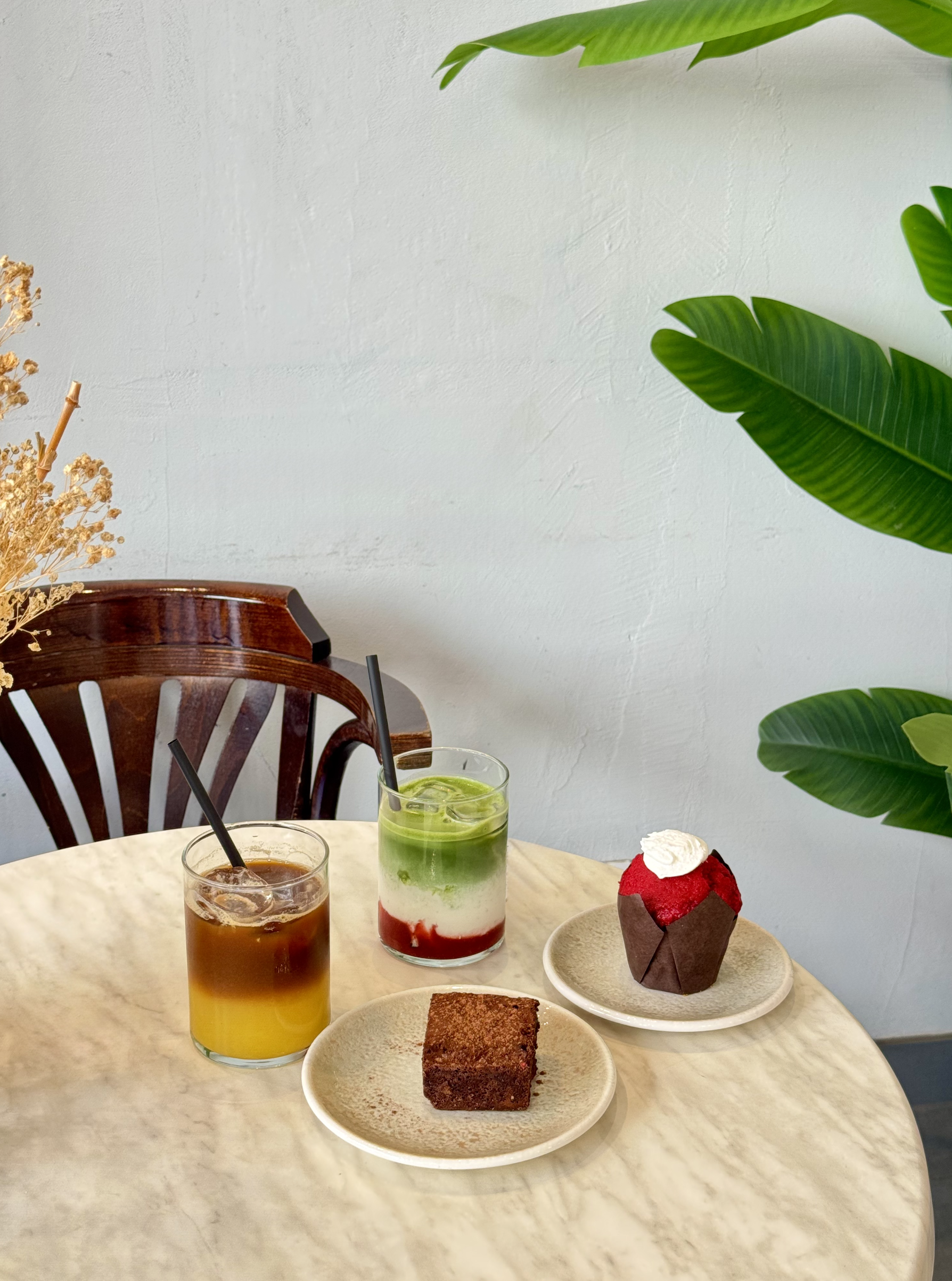 Mesa con dos bebidas, un pastel de chocolate y un cupcake.