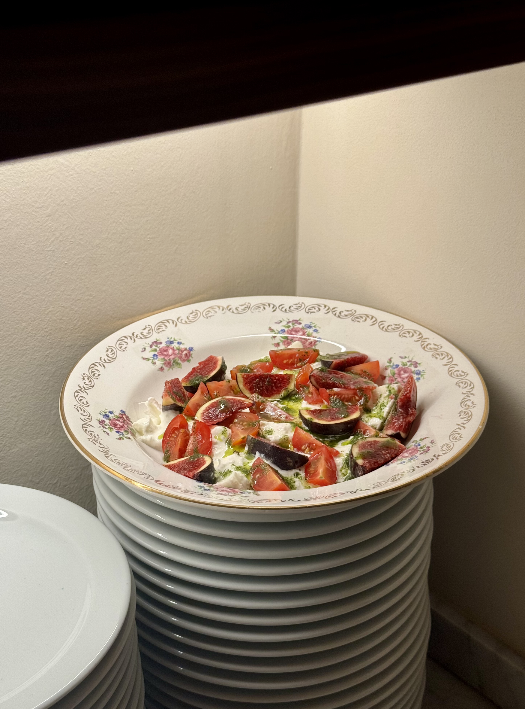 En un plato de comida. Está colocado sobre una pila de platos blancos apilados.