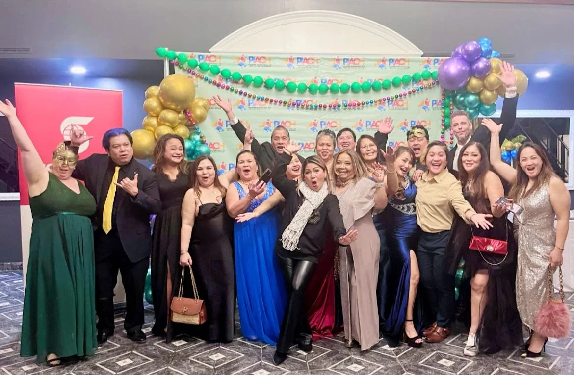 Group of people celebrating at an event with festive decorations, balloons, and a backdrop with the PAC logo, all smiling and posing for the camera.