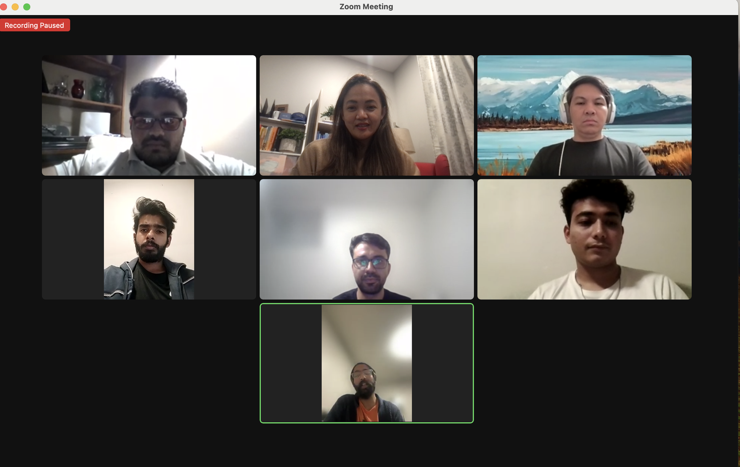 A screenshot of a Zoom virtual meeting with seven participants, six of whom are visible in individual video boxes and one with his video turned off, with a participant in the bottom box blurred. The participants are diverse and appear to be engaged in the meeting.