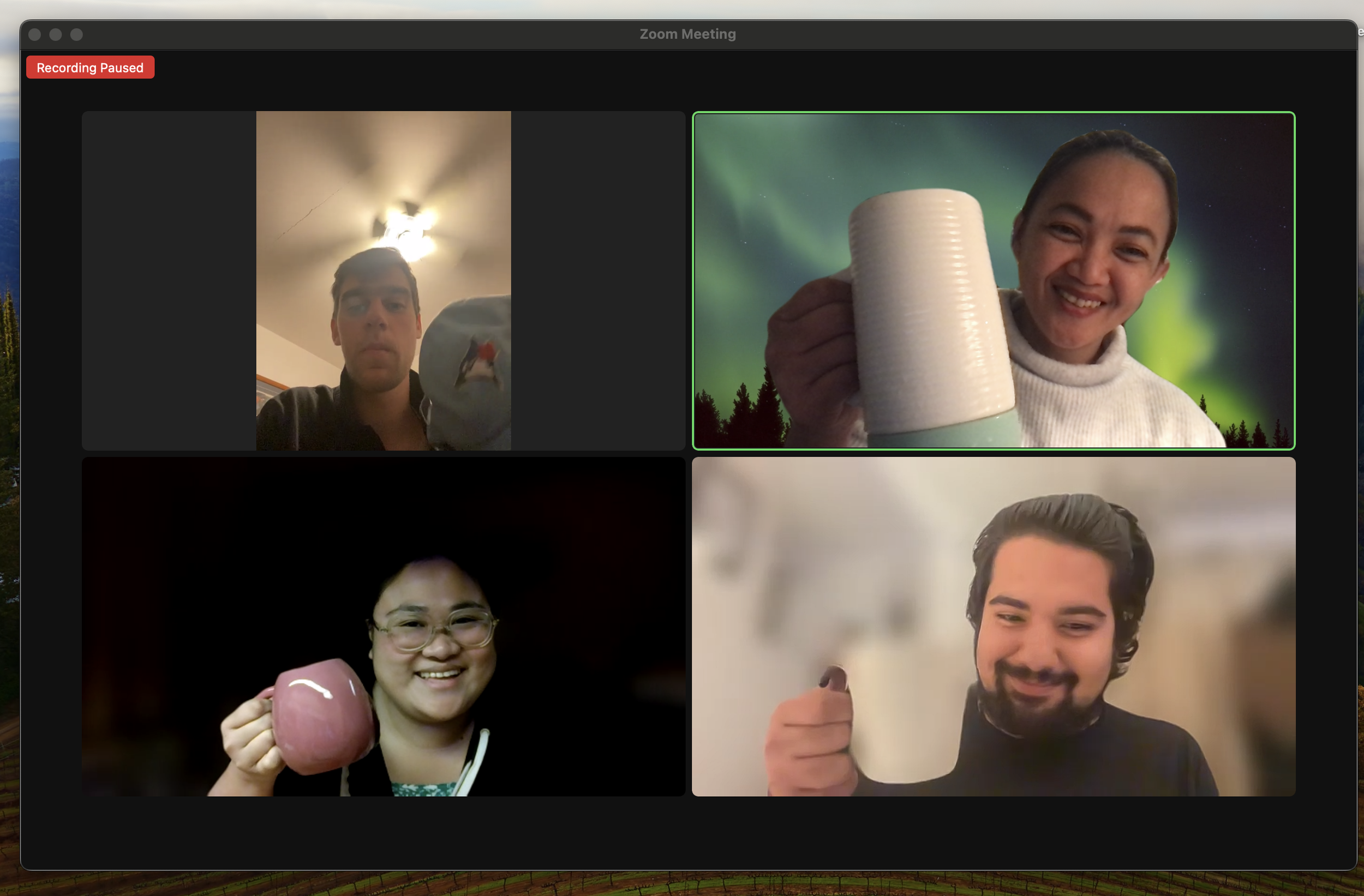 Four people participating in a virtual meeting, each holding a mug.