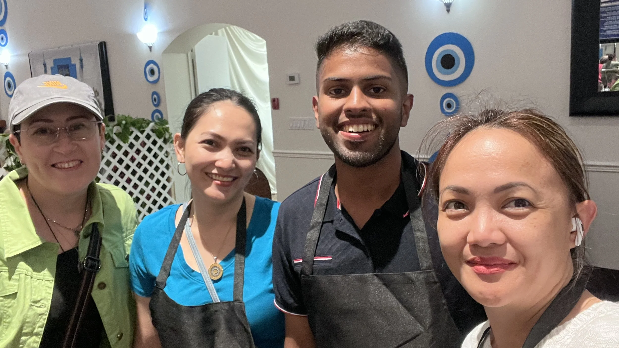 Four people smiling for a group photo indoors, with blue and white circular wall decorations in the background.