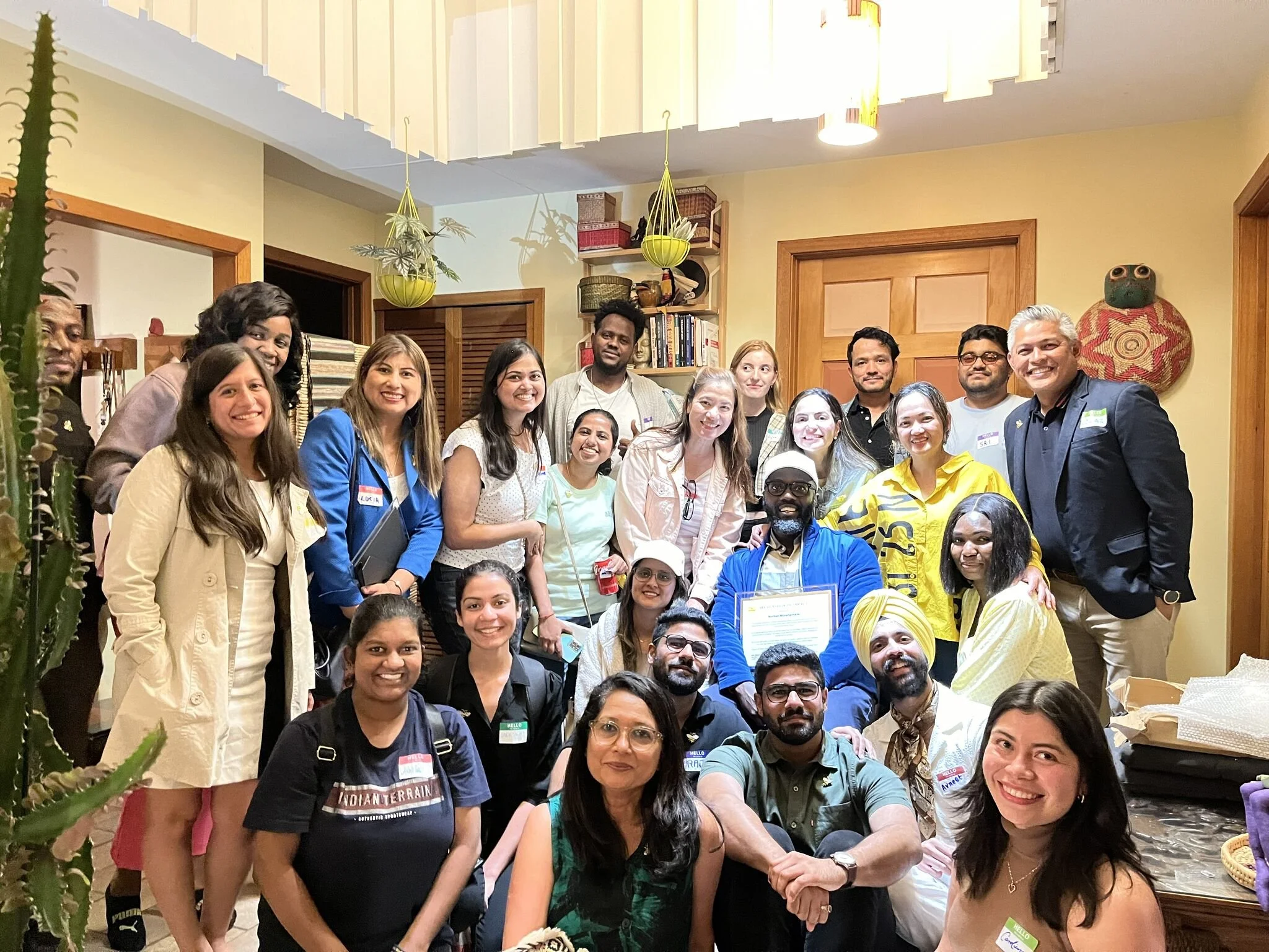 A group of diverse people gathered indoors, smiling for a group photo.