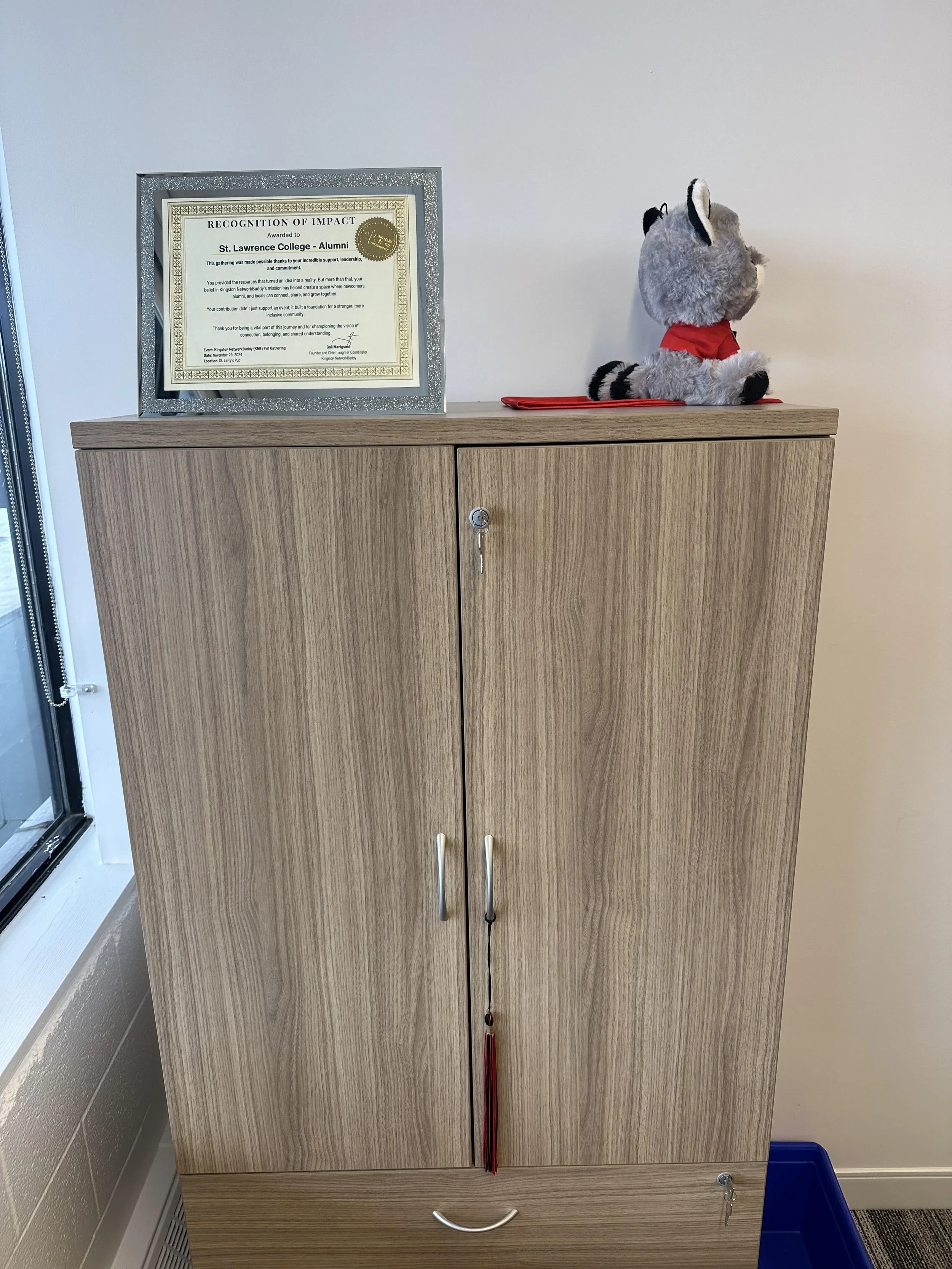 Wooden cabinet with a framed certificate and stuffed animal on top