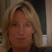 A woman with blonde hair, light skin, and blue eyes looking at the camera.