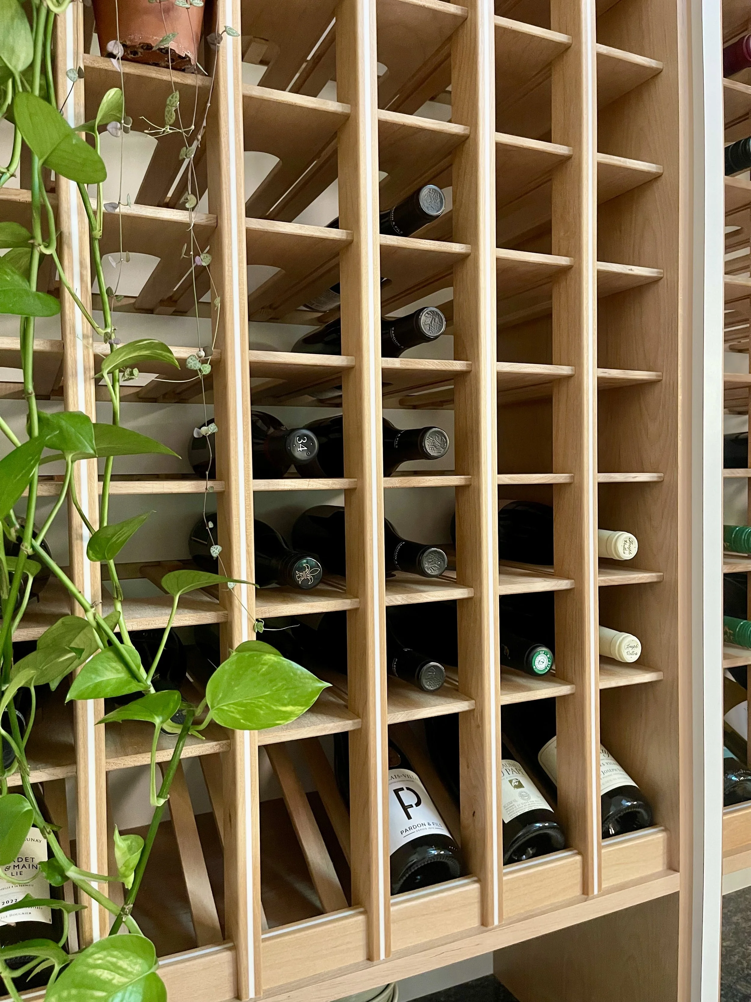 Kitchen countertop wine storage unit in Alder with white epoxy inlay and angular wine display area.

Wine Cellar project completed in Northville MI.