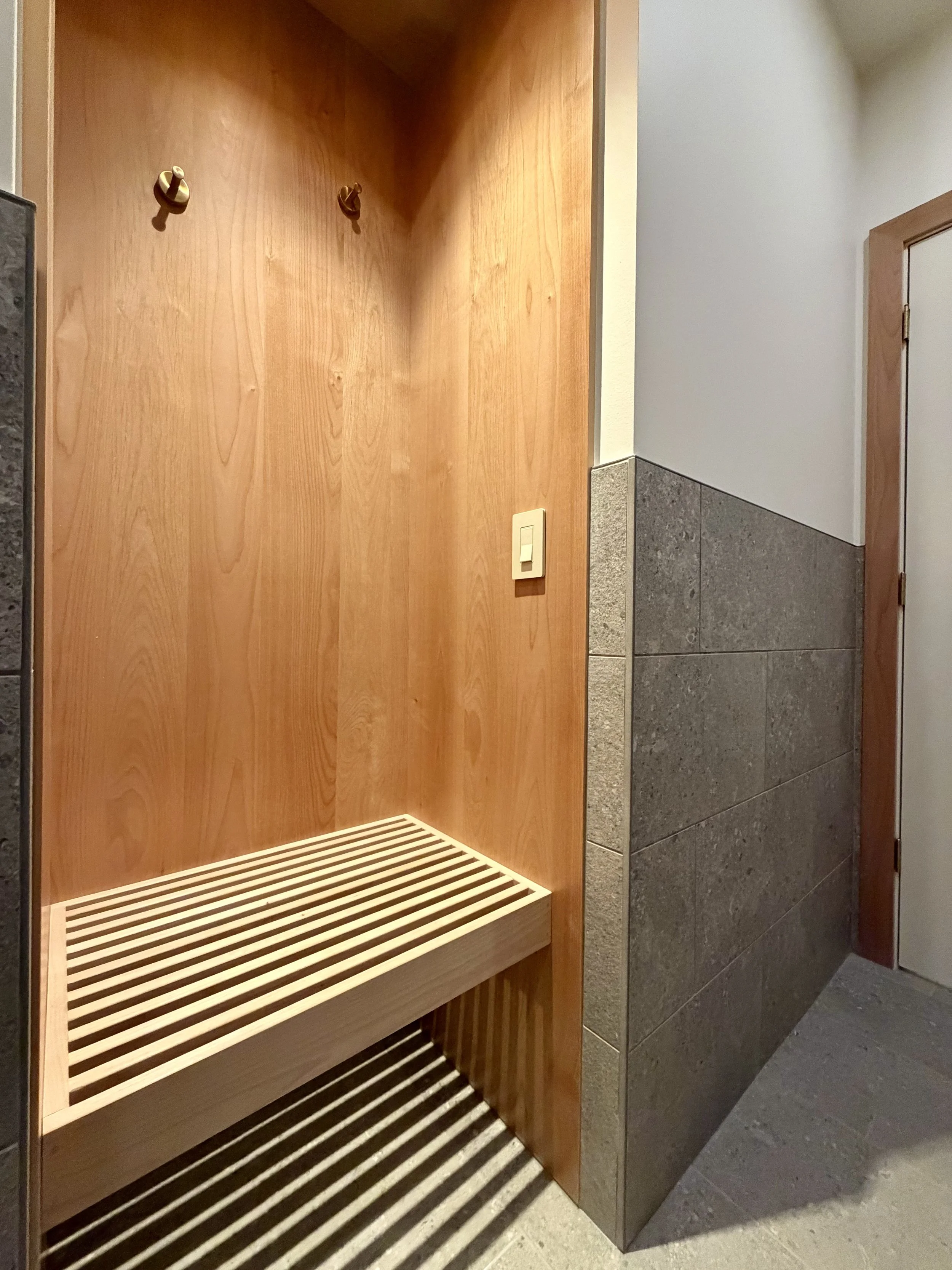 Foreground:
Custom Built Linear Changing Bench in 3/4" Alder Hardwood with Perimeter Wrapped in 3/4" Alder Plywood Finished with Centurion 2K Polyurethane. 

Thermostatically Controlled Heated Floors Using Schluter DITRA-HEAT.

Scandinavian Inspired 