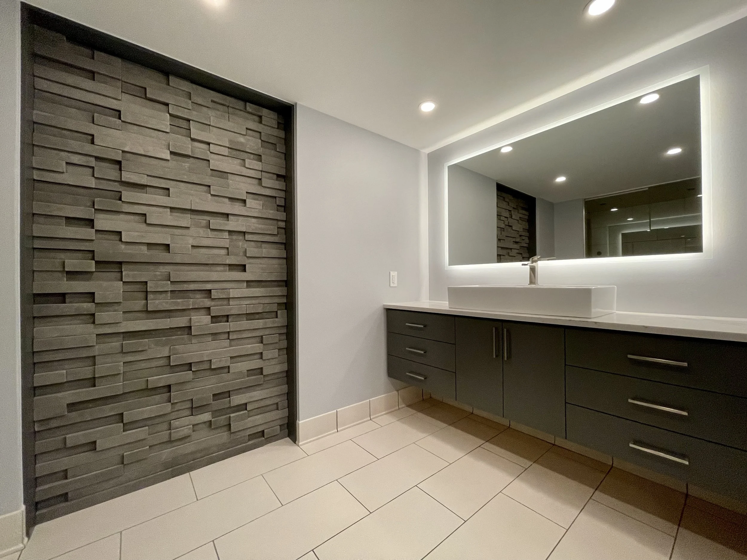 Custom Built Linear Vanity with Cultured Stone Accent Wall and Backlit Mirror 

Scandinavian Inspired Bathroom Remodeling Project With Custom Sauna and Steam Shower Completed in Northville MI. 